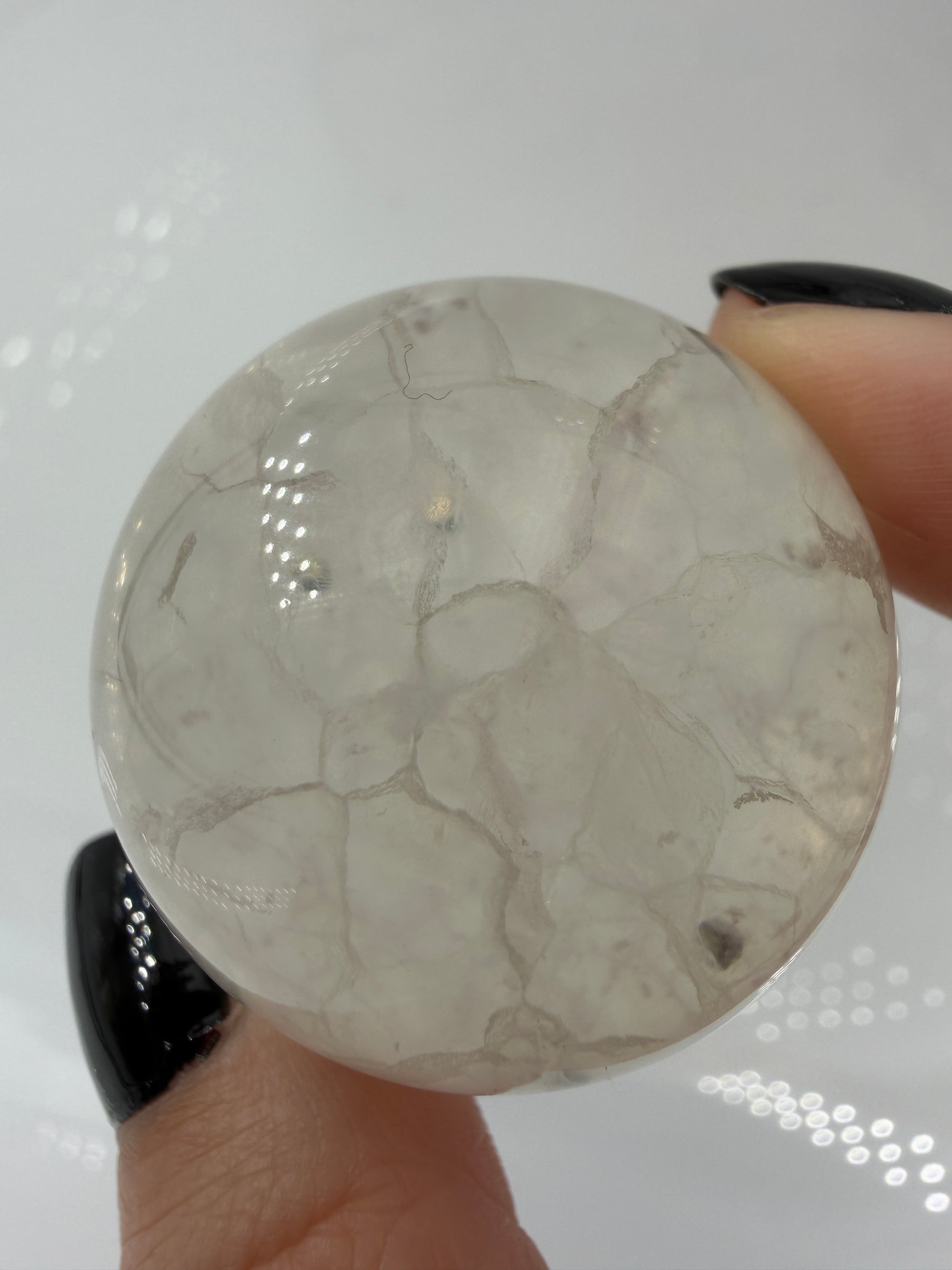 Polierte weiße Fluorit-Kugel mit deutlich erkennbaren, goldfarben glänzenden Pyrit-Kristallen.