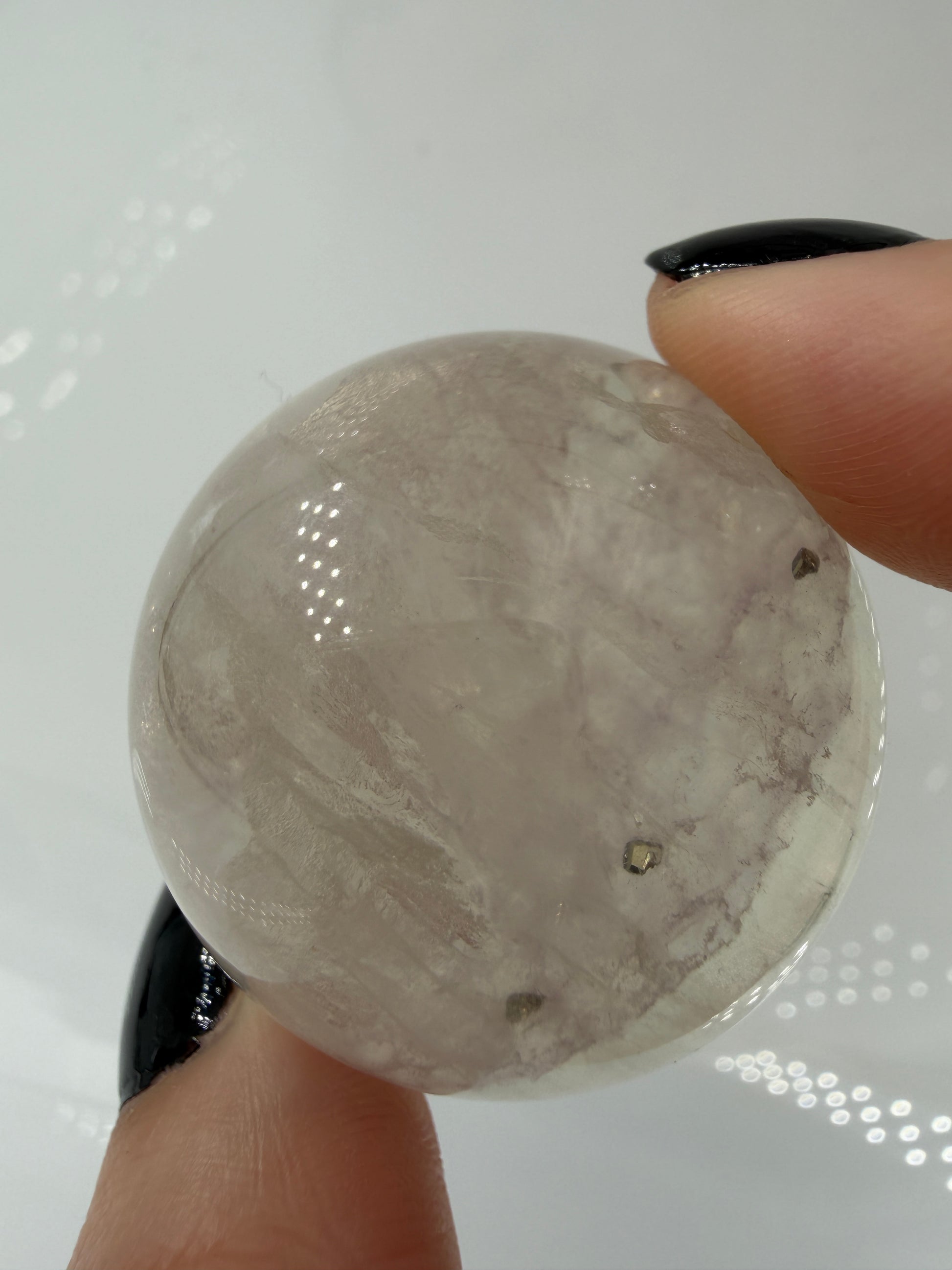 Polierte weiße Fluorit-Kugel mit deutlich erkennbaren, goldfarben glänzenden Pyrit-Kristallen.