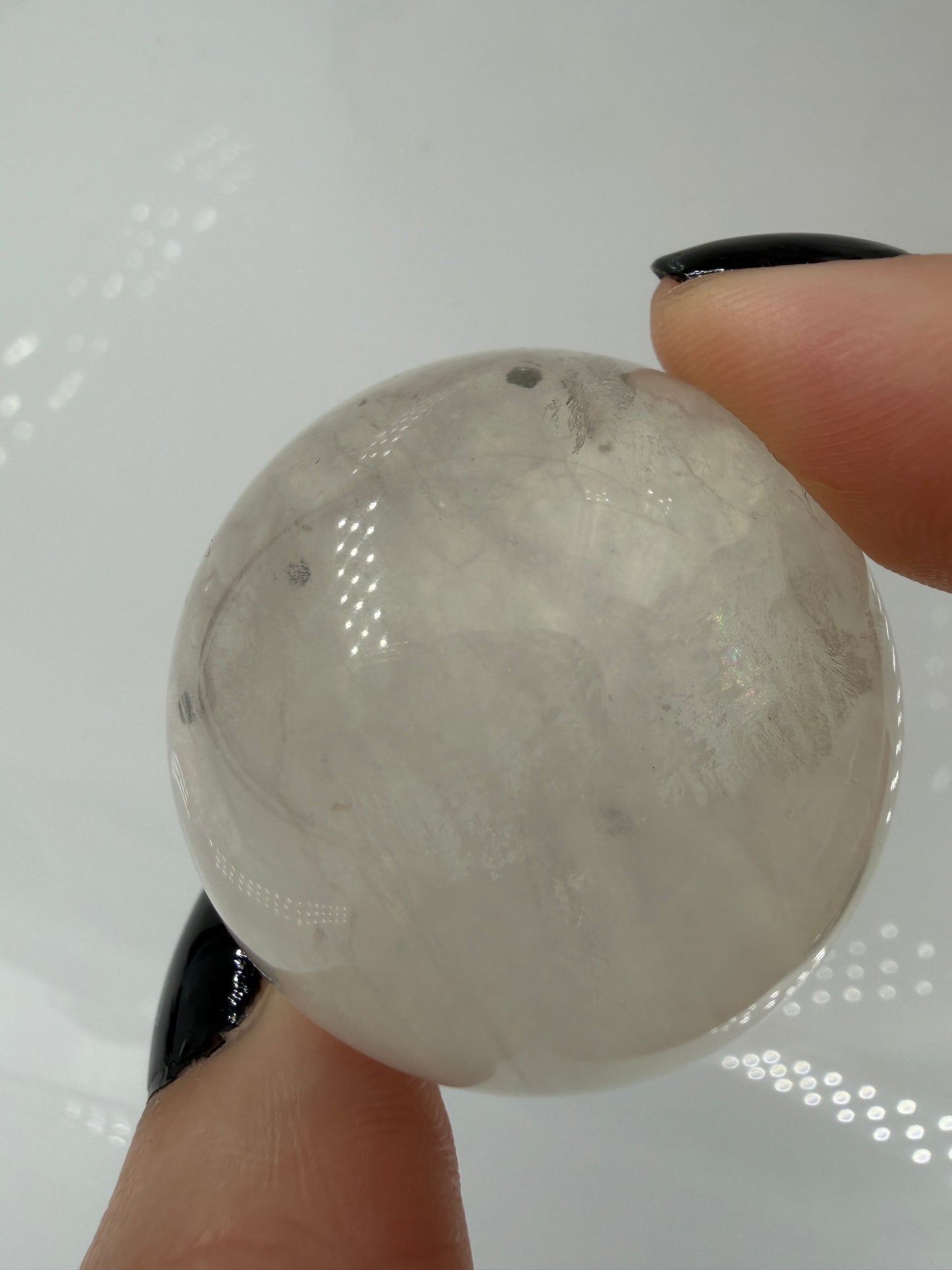 Polierte weiße Fluorit-Kugel mit deutlich erkennbaren, goldfarben glänzenden Pyrit-Kristallen.