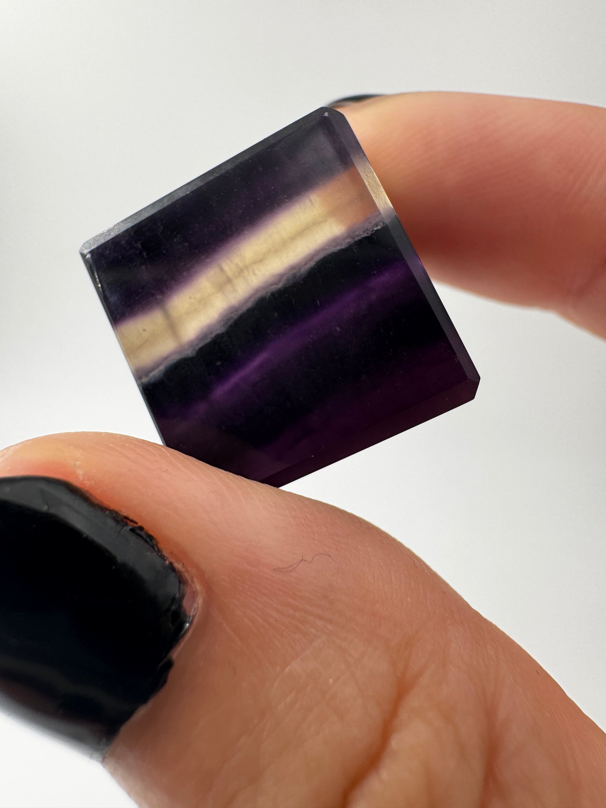 Ein transparenter Fluorit-Würfel mit deutlich sichtbaren violetten Farbbändern.