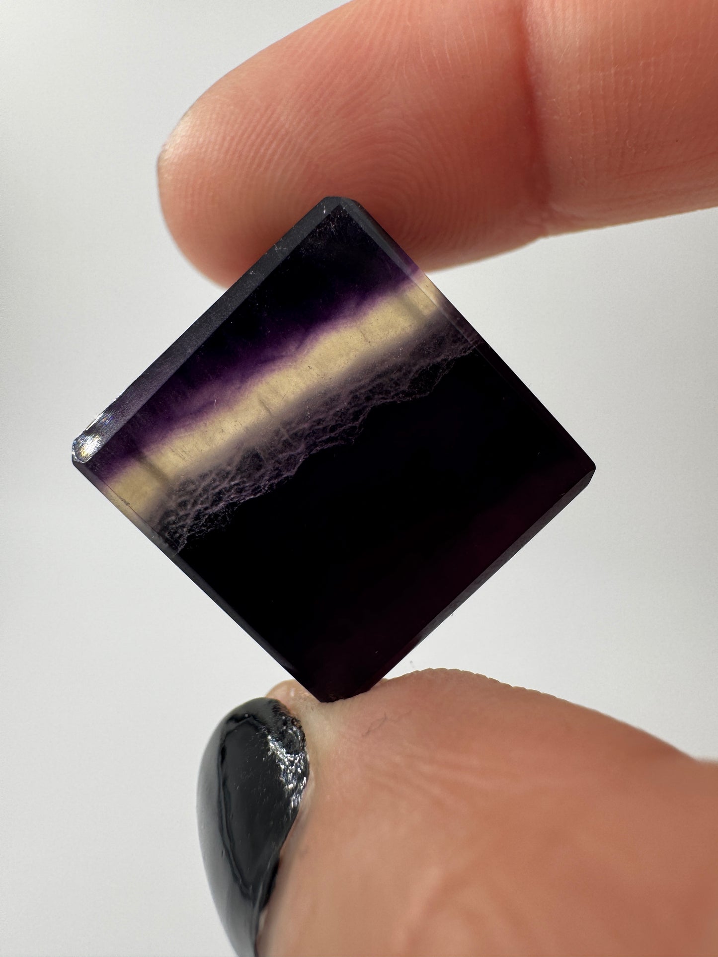 Ein transparenter Fluorit-Würfel mit deutlich sichtbaren violetten Farbbändern.