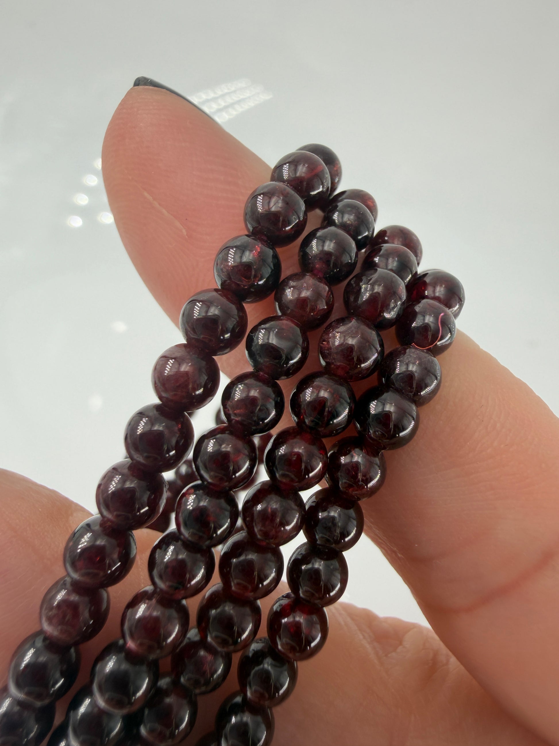 Dunkelrotes Kugelarmband aus poliertem Granat auf einem elastischen Band für Kinder.