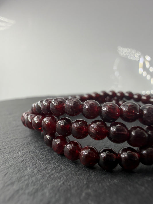 Dunkelrotes Kugelarmband aus poliertem Granat auf einem elastischen Band für Kinder.