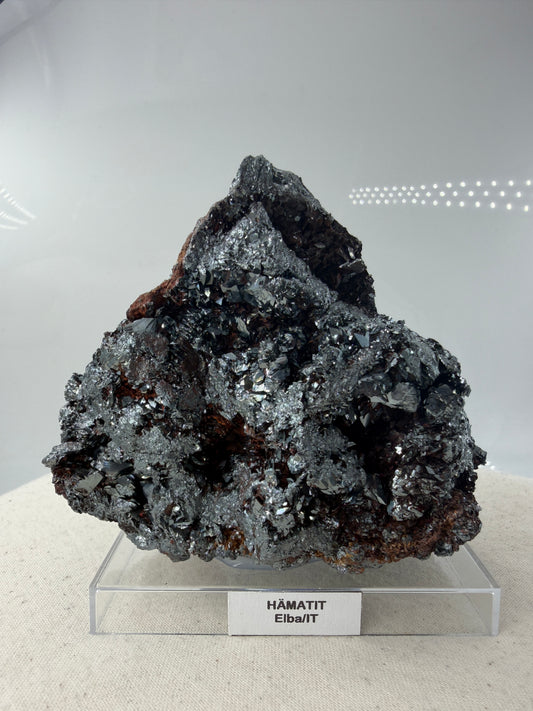 Hämatit-Specimen aus Elba, Italien, mit hochglänzenden, metallischen Mineralkristallen und charakteristischer linsenförmiger Struktur.