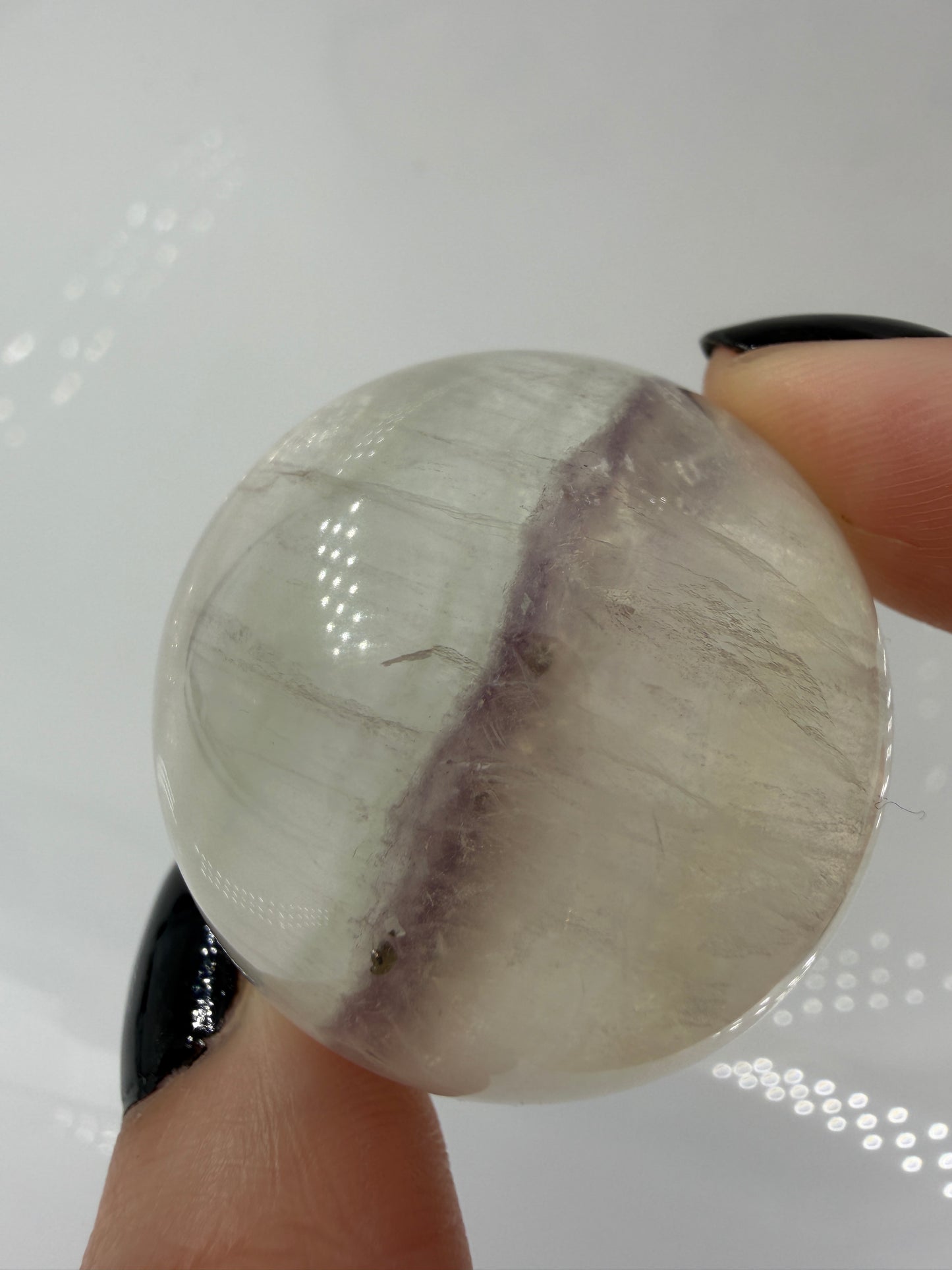 Polierte weiße Fluorit-Kugel mit deutlich erkennbaren, goldfarben glänzenden Pyrit-Kristallen.