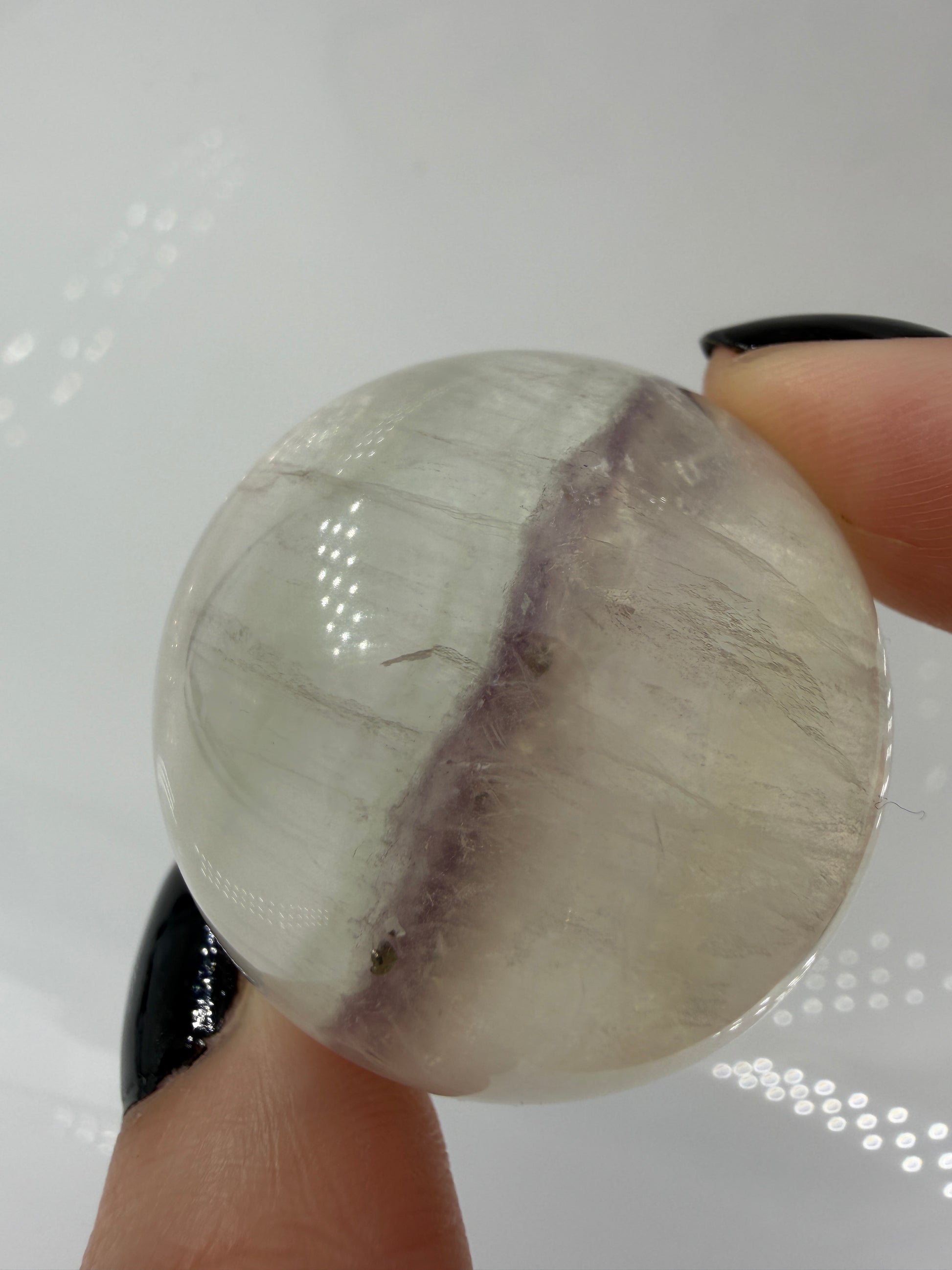 Polierte weiße Fluorit-Kugel mit deutlich erkennbaren, goldfarben glänzenden Pyrit-Kristallen.