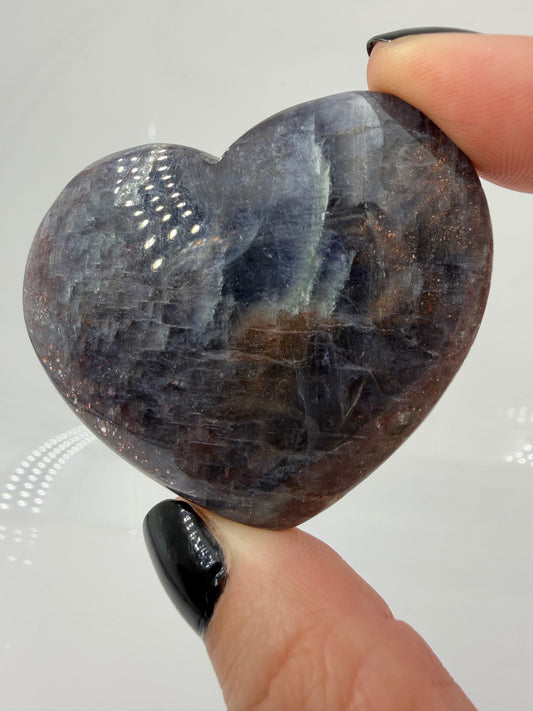 Ein Herz aus dunkelblauem Iolith, mit Sonnenstein. Die glatte Oberfläche zeigt je nach Lichteinfall einen metallischen Glanz und die charakteristischen Farbumschläge der beiden Mineralvarianten.