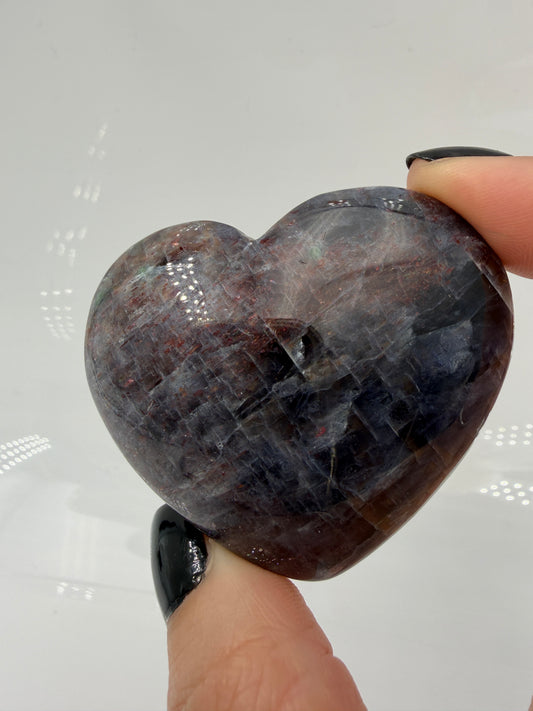 Ein Herz aus dunkelblauem Iolith, mit Sonnenstein. Die glatte Oberfläche zeigt je nach Lichteinfall einen metallischen Glanz und die charakteristischen Farbumschläge der beiden Mineralvarianten.
