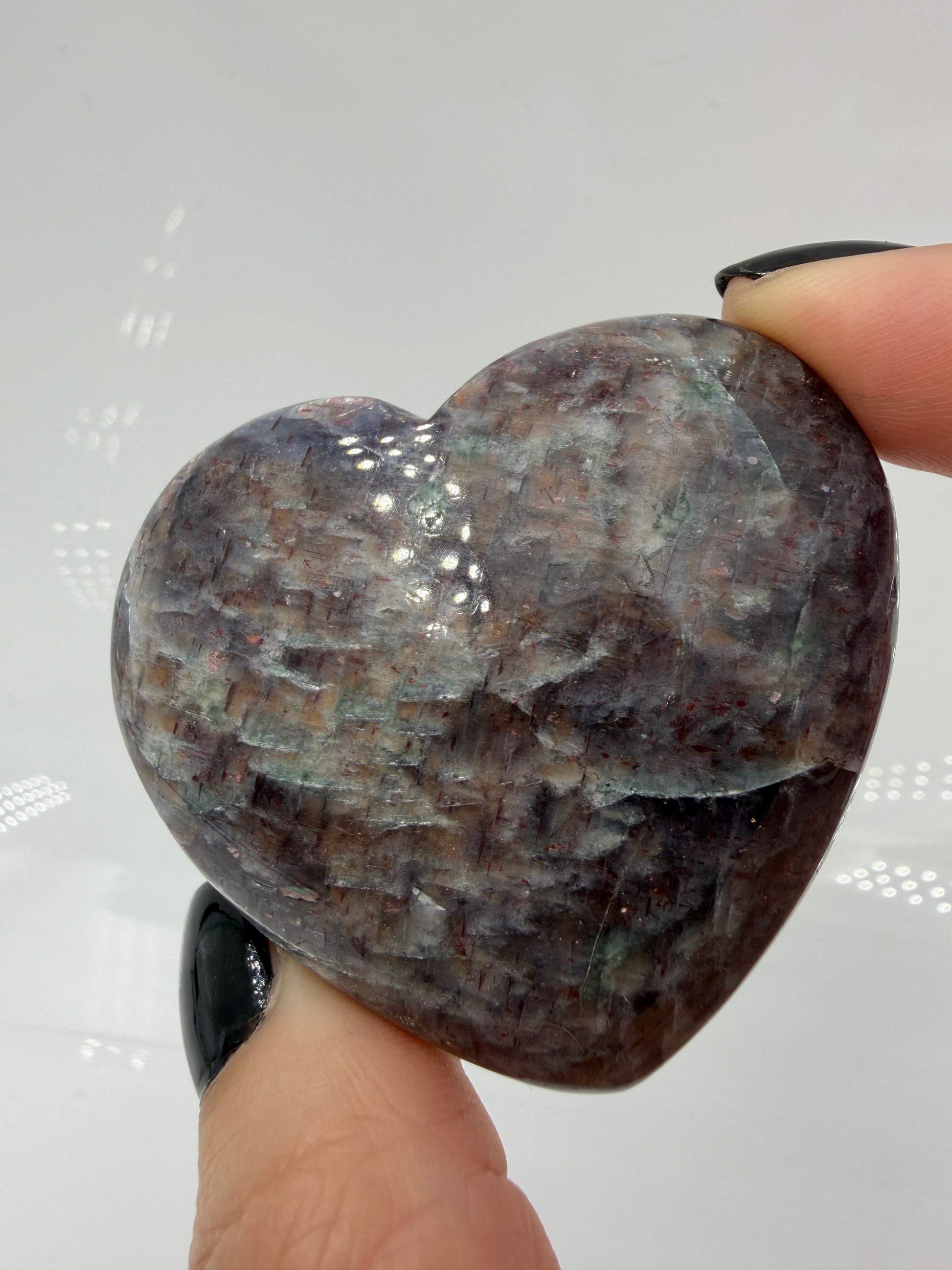 Ein Herz aus dunkelblauem Iolith, mit Sonnenstein. Die glatte Oberfläche zeigt je nach Lichteinfall einen metallischen Glanz und die charakteristischen Farbumschläge der beiden Mineralvarianten.