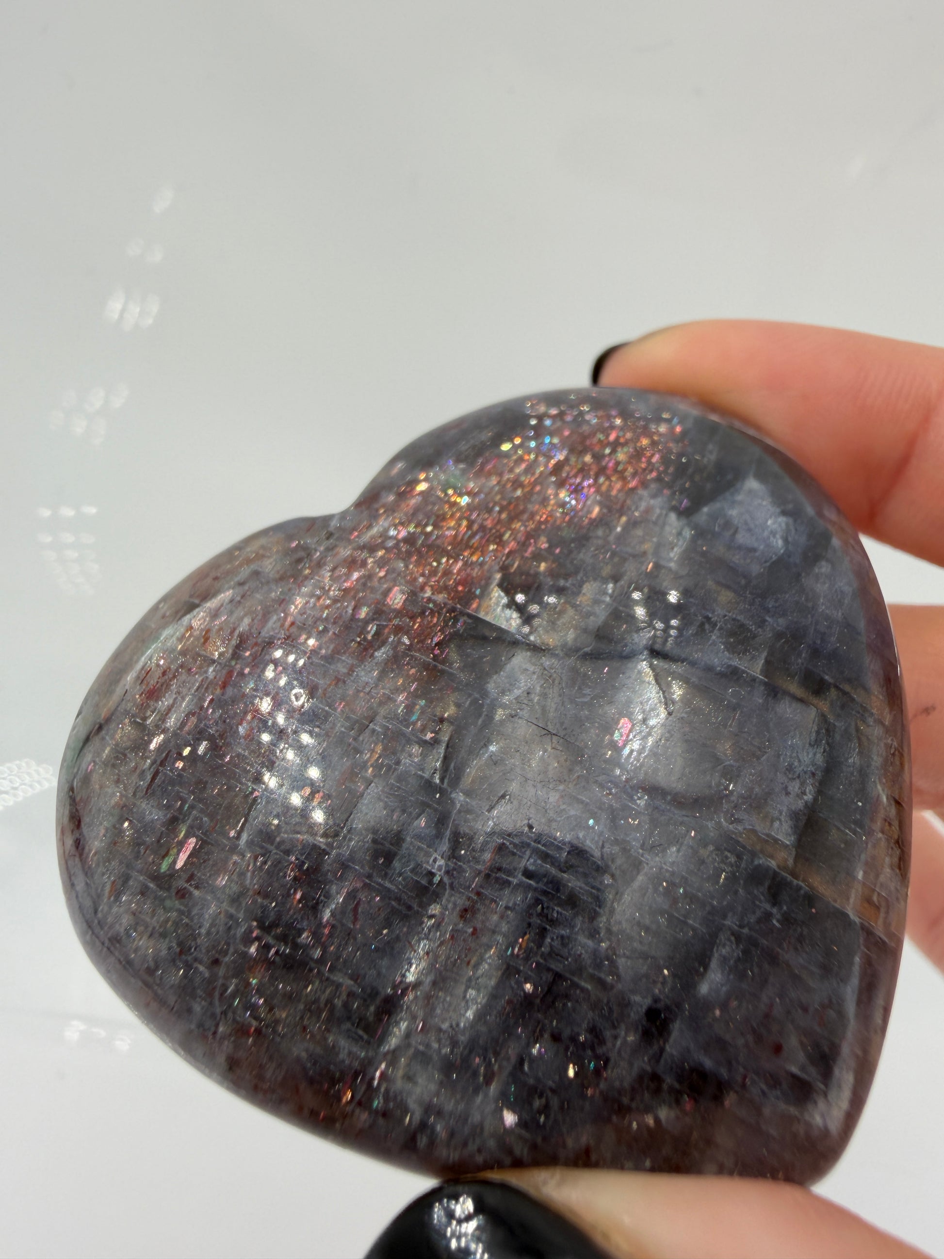 Ein Herz aus dunkelblauem Iolith, mit Sonnenstein. Die glatte Oberfläche zeigt je nach Lichteinfall einen metallischen Glanz und die charakteristischen Farbumschläge der beiden Mineralvarianten.