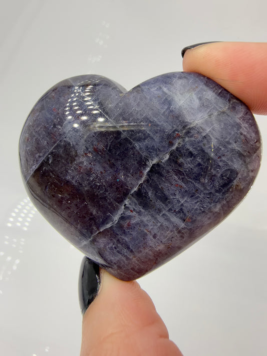 Ein Herz aus dunkelblauem Iolith, mit Sonnenstein. Die glatte Oberfläche zeigt je nach Lichteinfall einen metallischen Glanz und die charakteristischen Farbumschläge der beiden Mineralvarianten.