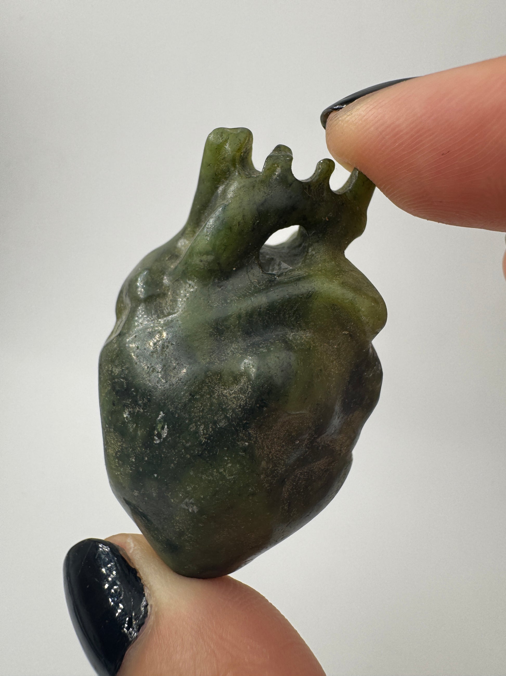 Ein fein skulpturiertes anatomisches Herz aus grüner Jade mit detailgetreuen Arterien und einer sanft schimmernden Oberfläche.