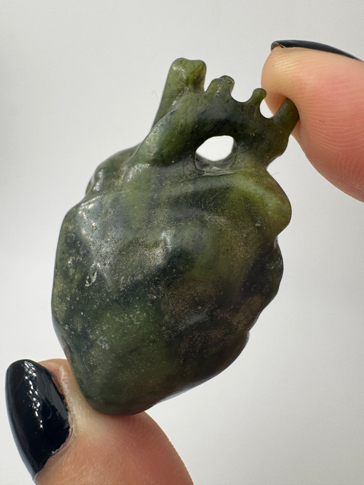 Ein fein skulpturiertes anatomisches Herz aus grüner Jade mit detailgetreuen Arterien und einer sanft schimmernden Oberfläche.