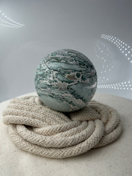 Eine perfekt polierte Kugel aus indischem Jaspis mit einem lebhaften Muster aus grünem und weißen Mineralbändern, die eine faszinierende, natürliche Textur bilden.