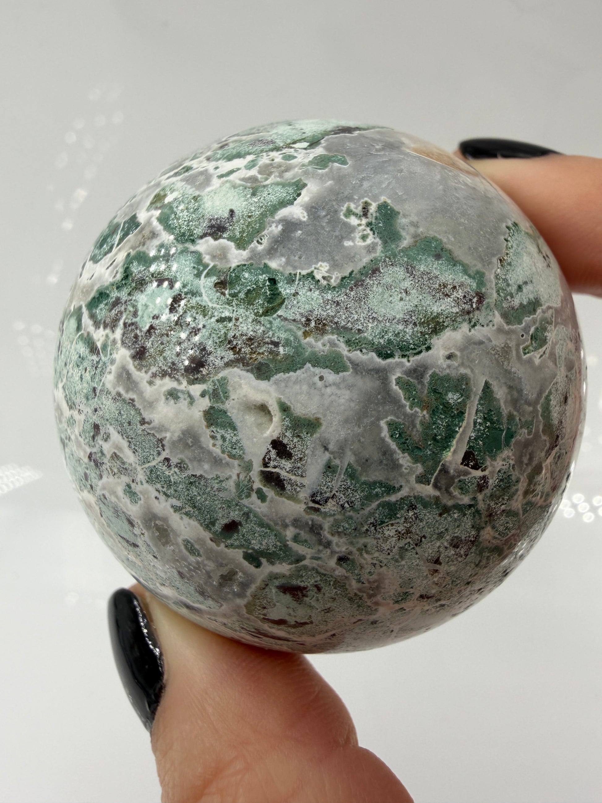 Eine perfekt polierte Kugel aus indischem Jaspis mit einem lebhaften Muster aus grünem und weißen Mineralbändern, die eine faszinierende, natürliche Textur bilden.