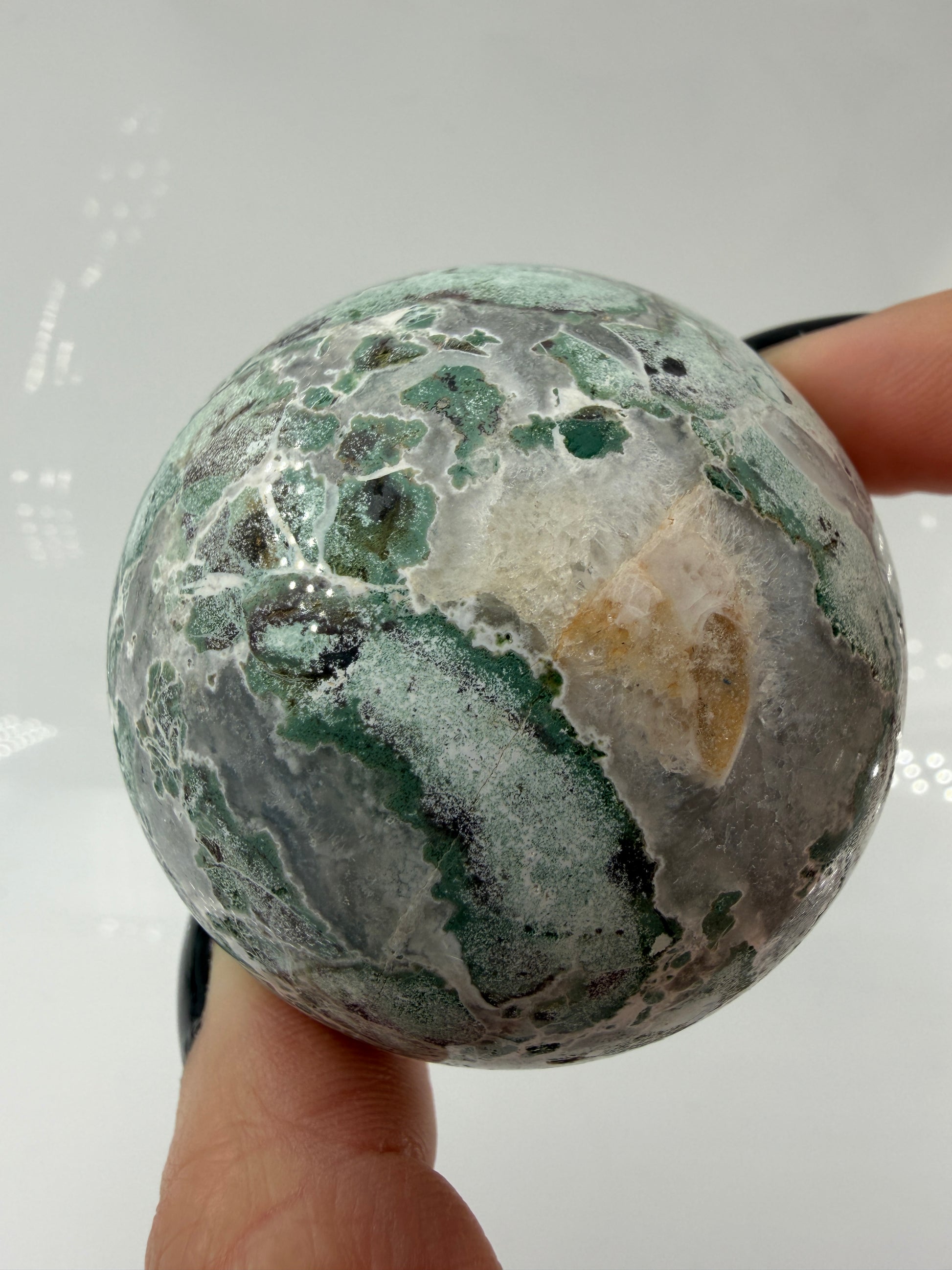 Eine perfekt polierte Kugel aus indischem Jaspis mit einem lebhaften Muster aus grünem und weißen Mineralbändern, die eine faszinierende, natürliche Textur bilden.
