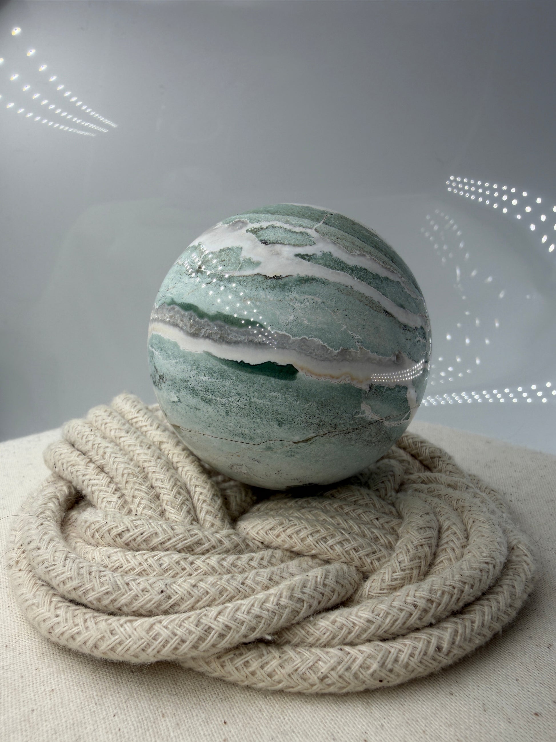 Eine perfekt polierte Kugel aus indischem Jaspis mit einem lebhaften Muster aus grünem und weißen Mineralbändern, die eine faszinierende, natürliche Textur bilden.