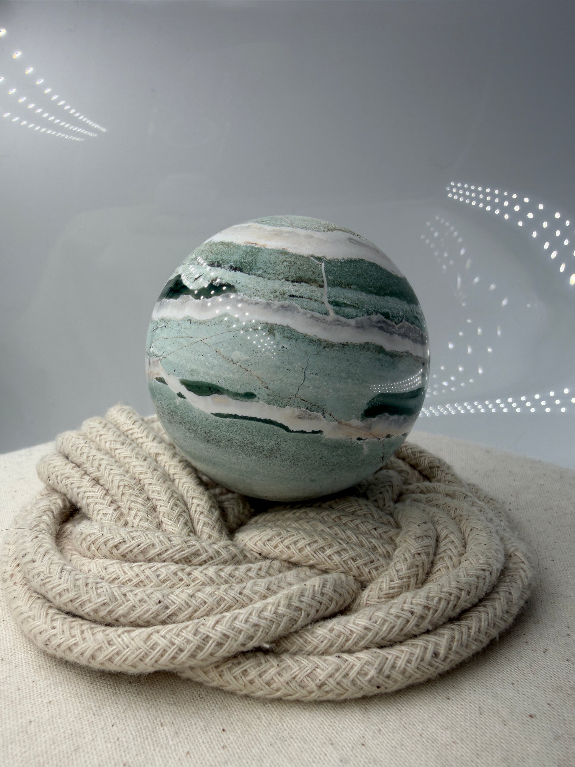 Eine perfekt polierte Kugel aus indischem Jaspis mit einem lebhaften Muster aus grünem und weißen Mineralbändern, die eine faszinierende, natürliche Textur bilden.