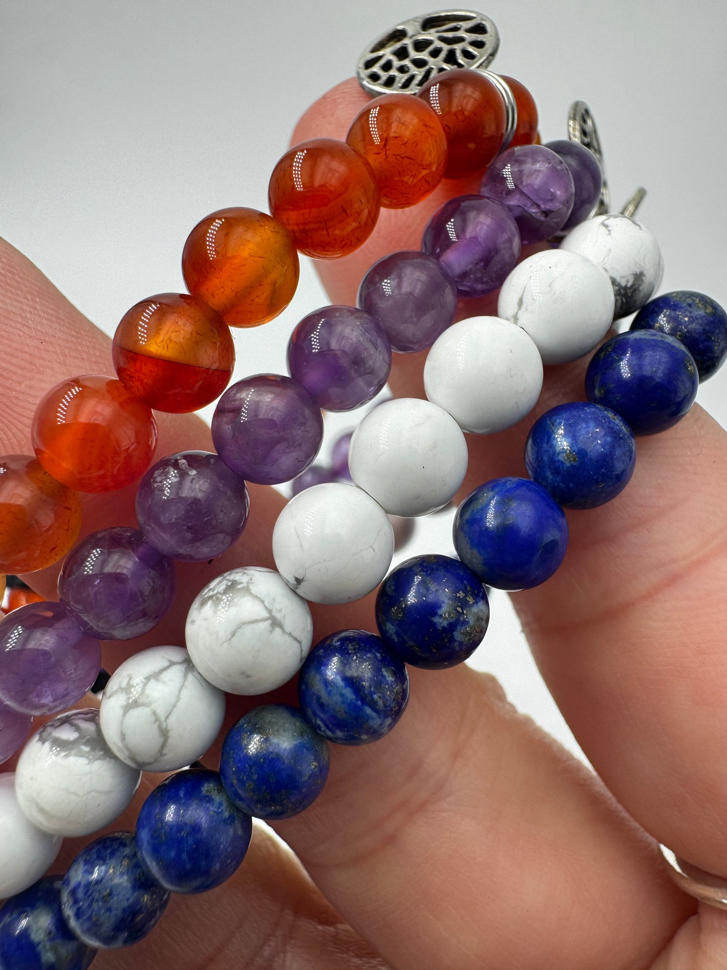 Kugelarmbänder aus Karneol, Amethyst, Magnesit und Lapislazuli mit Lebensbaum-Anhänger.