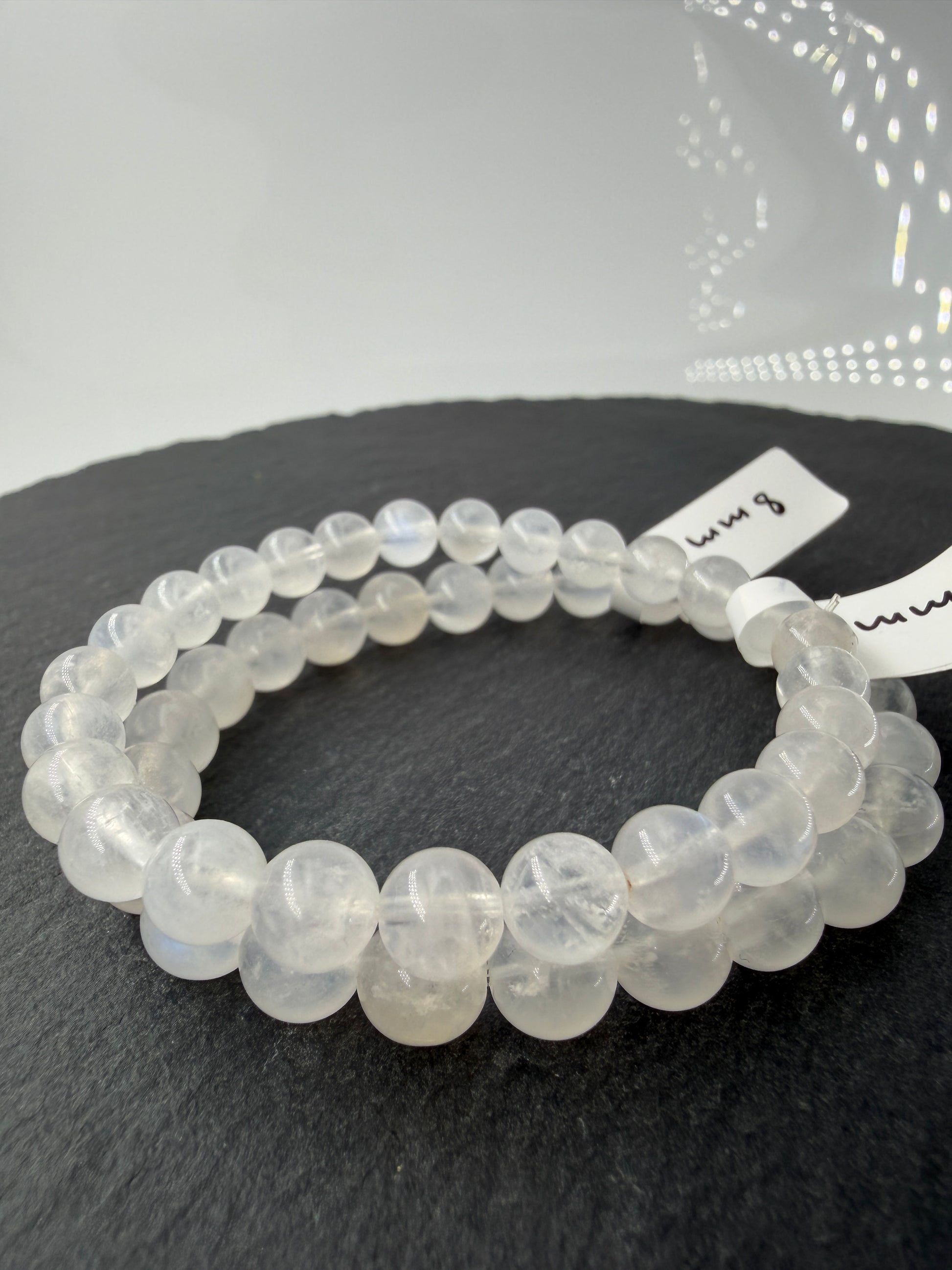 Ein elegantes Armband aus polierten, weiß-transparenten Labradorit-Kugeln, die bei Lichteinfall einen intensiven, elektrisch blauen Schimmer auf ihrer Oberfläche zeigen.