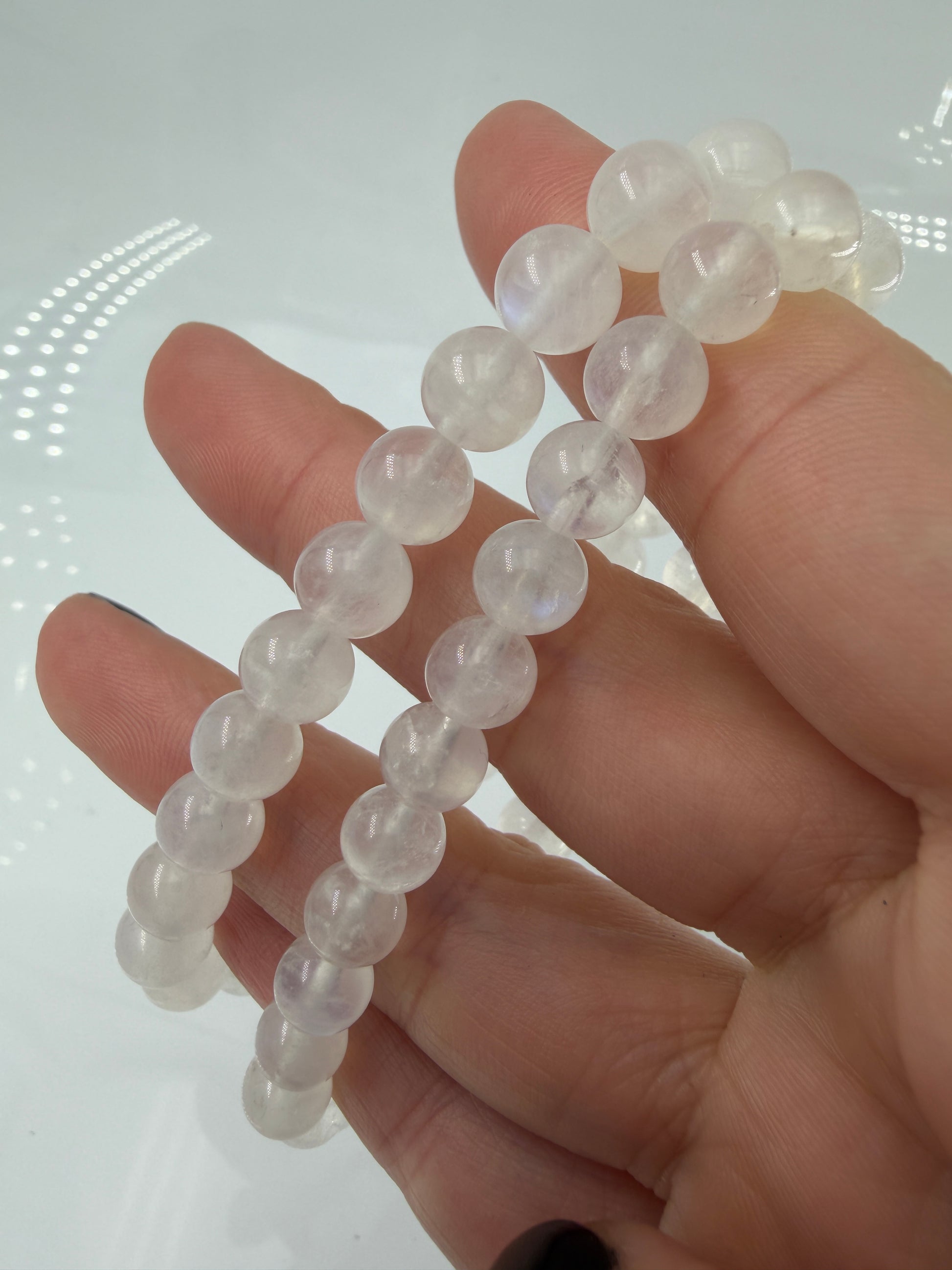 Ein elegantes Armband aus polierten, weiß-transparenten Labradorit-Kugeln, die bei Lichteinfall einen intensiven, elektrisch blauen Schimmer auf ihrer Oberfläche zeigen.