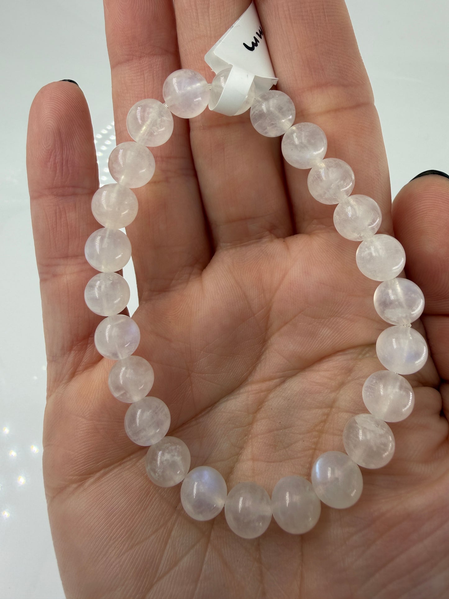 Ein elegantes Armband aus polierten, weiß-transparenten Labradorit-Kugeln, die bei Lichteinfall einen intensiven, elektrisch blauen Schimmer auf ihrer Oberfläche zeigen.