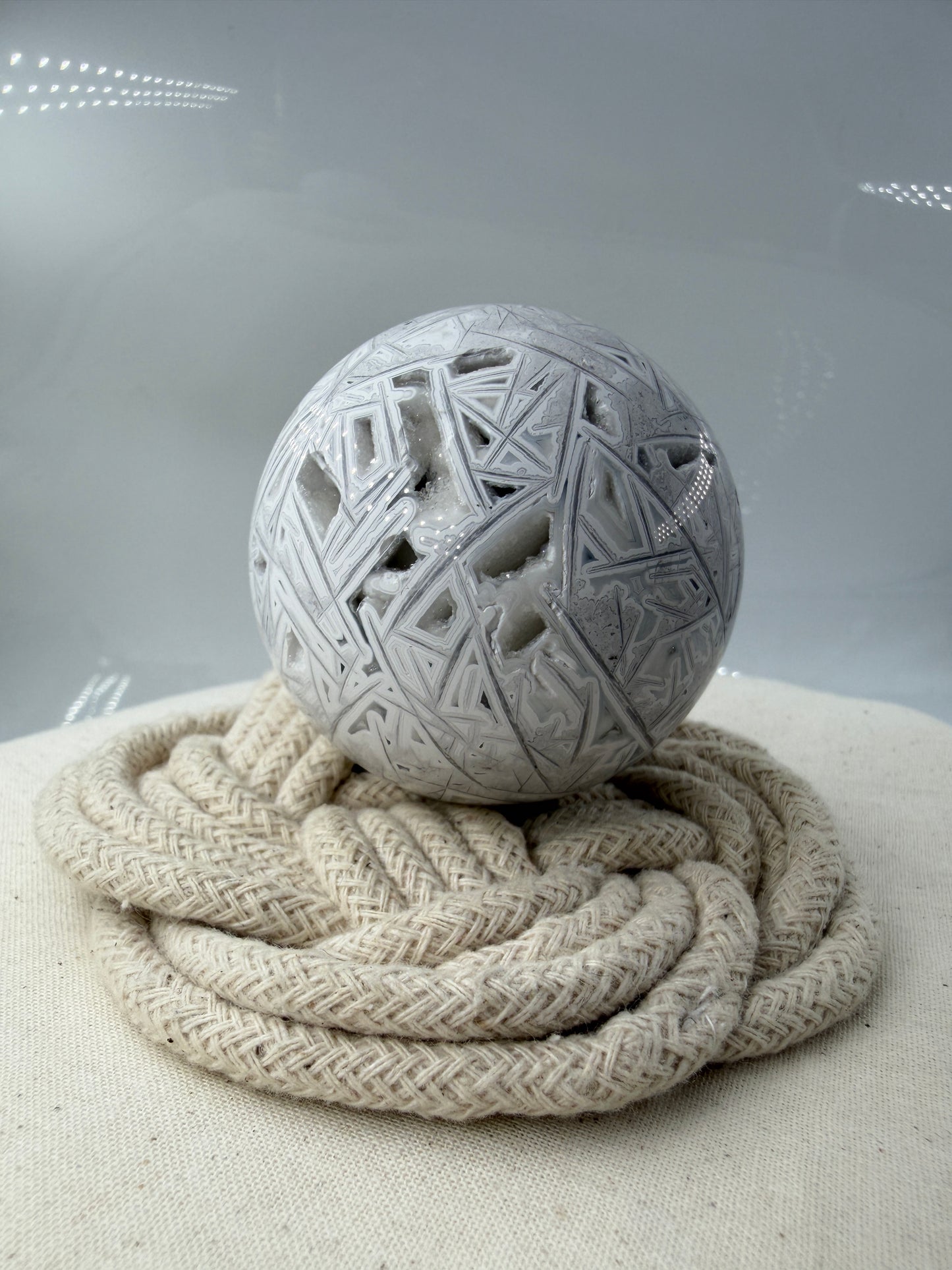 Handpolierte Lace Achat Kugel in Weiß und Grau mit natürlichen Drusen und charakteristischen Bänderungen, Ø 5,9 cm – edles Sammlerstück aus Quarz.