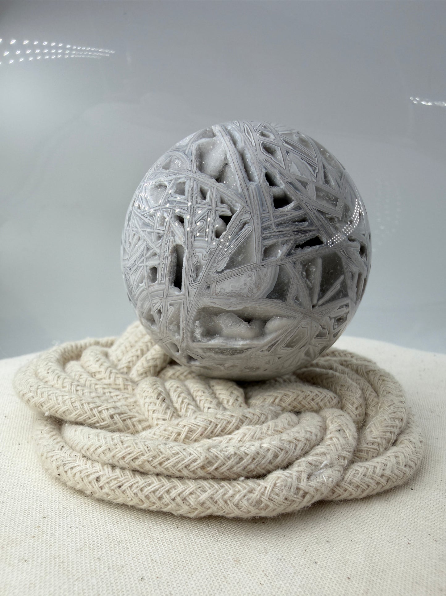 Handpolierte Lace Achat Kugel in Weiß und Grau mit natürlichen Drusen und charakteristischen Bänderungen, Ø 6,0 cm – edles Sammlerstück aus Quarz.