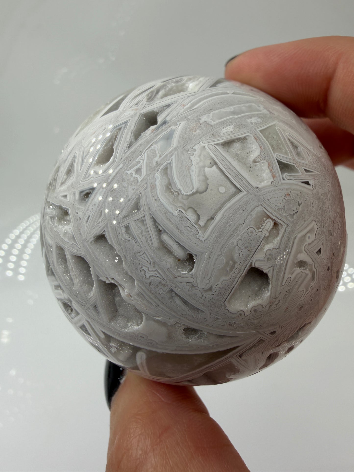 Handpolierte Lace Achat Kugel in Weiß und Grau mit natürlichen Drusen und charakteristischen Bänderungen, Ø 6,0 cm – edles Sammlerstück aus Quarz.
