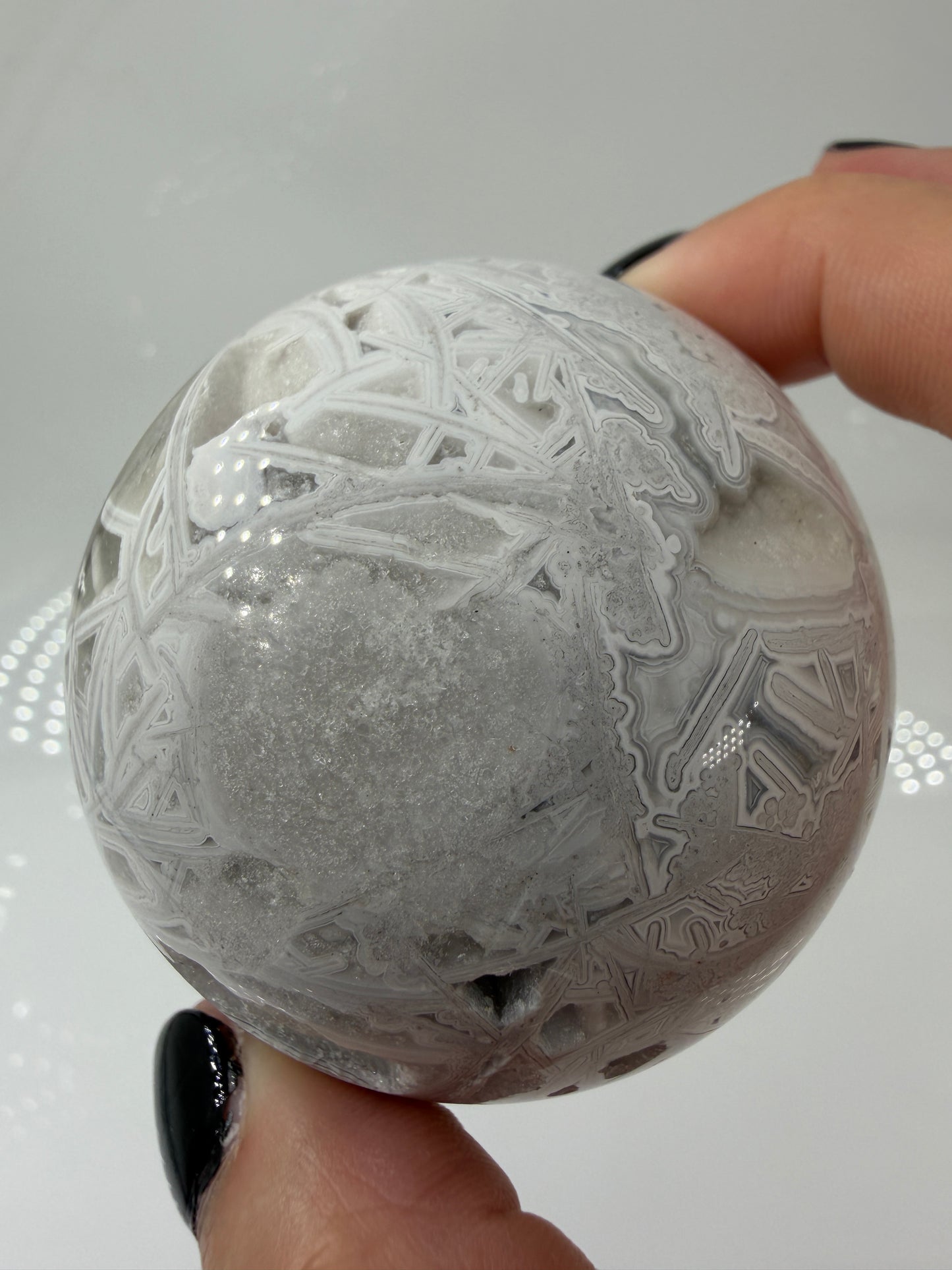 Handpolierte Lace Achat Kugel in Weiß und Grau mit natürlichen Drusen und charakteristischen Bänderungen, Ø 6,0 cm – edles Sammlerstück aus Quarz.