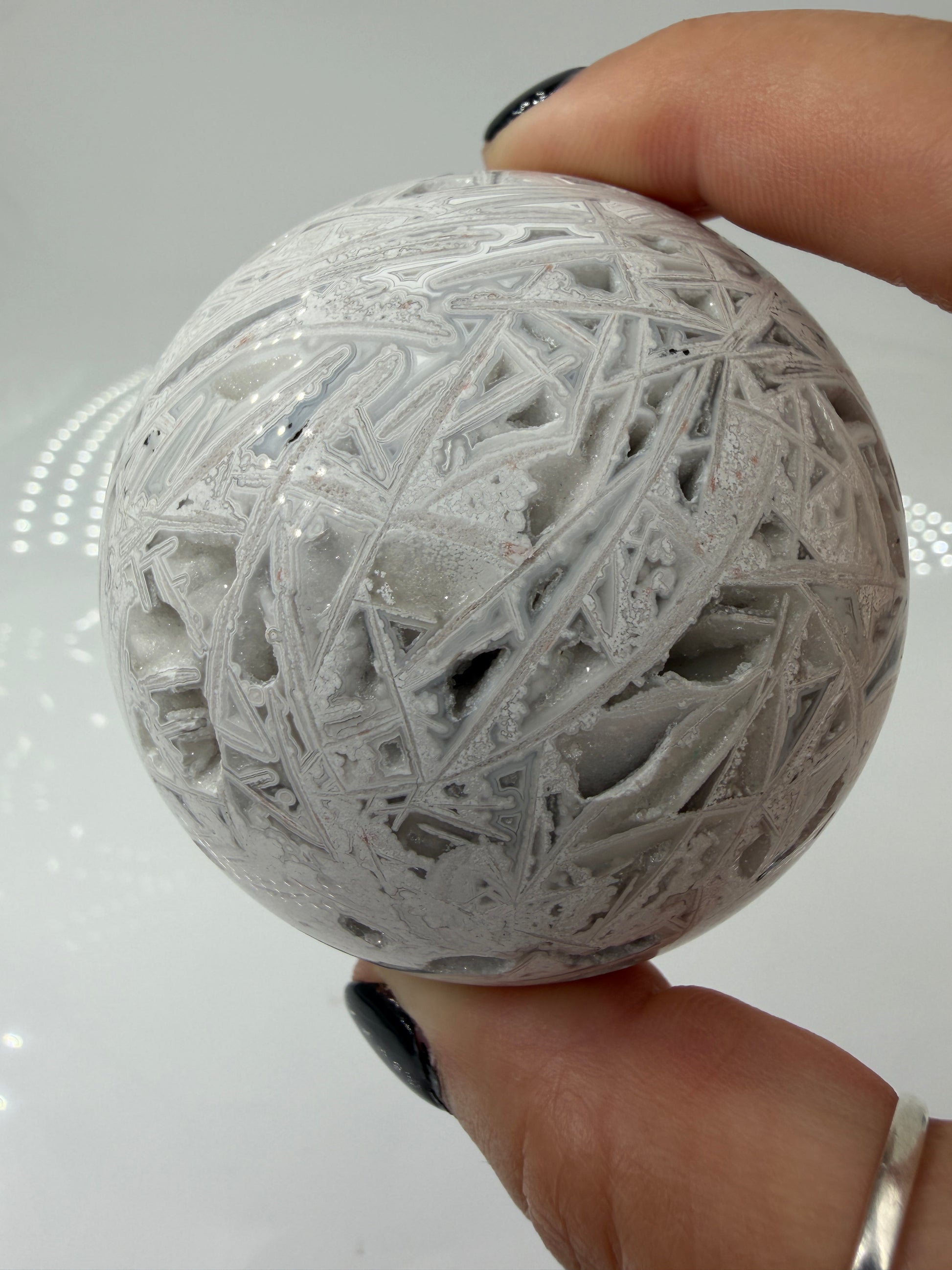 Handpolierte Lace Achat Kugel in Weiß und Grau mit natürlichen Drusen und charakteristischen Bänderungen, Ø 6,5 cm – edles Sammlerstück aus Quarz.