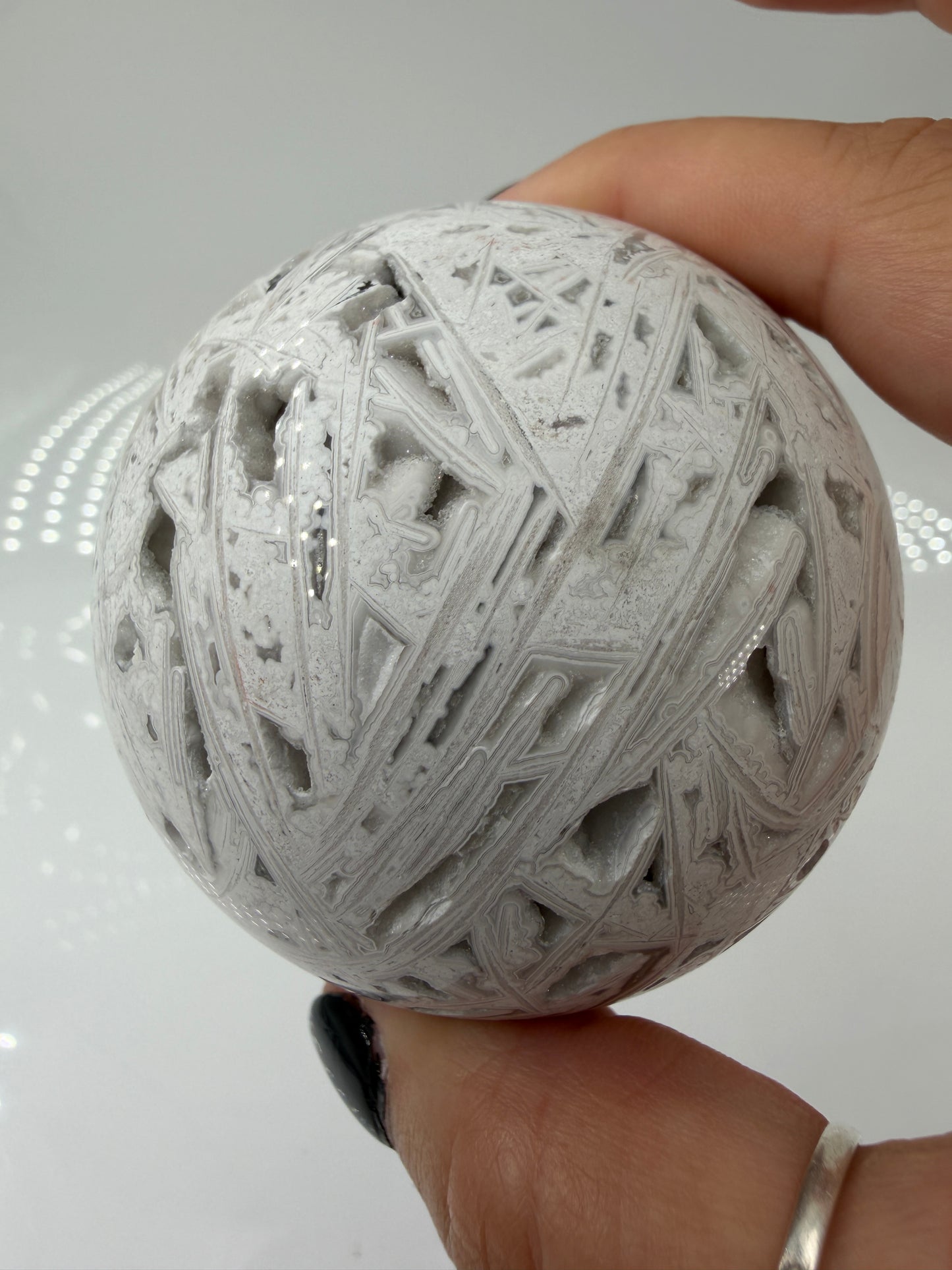 Handpolierte Lace Achat Kugel in Weiß und Grau mit natürlichen Drusen und charakteristischen Bänderungen, Ø 6,5 cm – edles Sammlerstück aus Quarz.