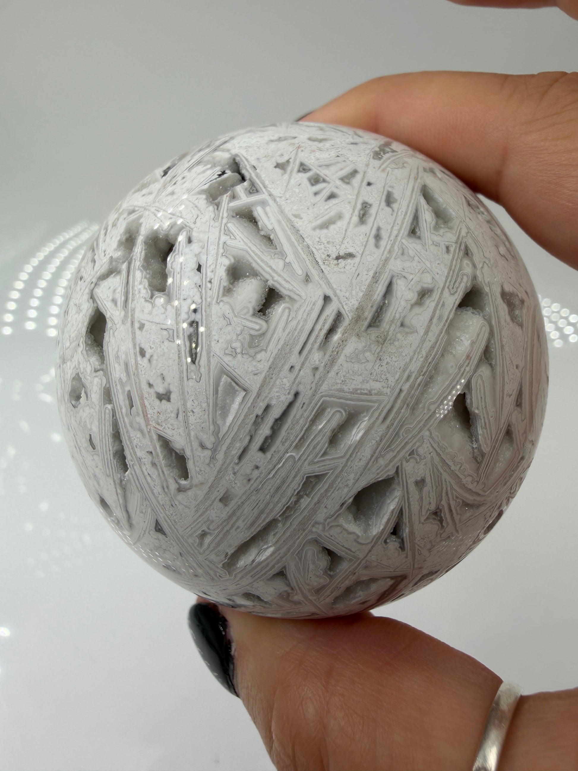 Handpolierte Lace Achat Kugel in Weiß und Grau mit natürlichen Drusen und charakteristischen Bänderungen, Ø 6,5 cm – edles Sammlerstück aus Quarz.