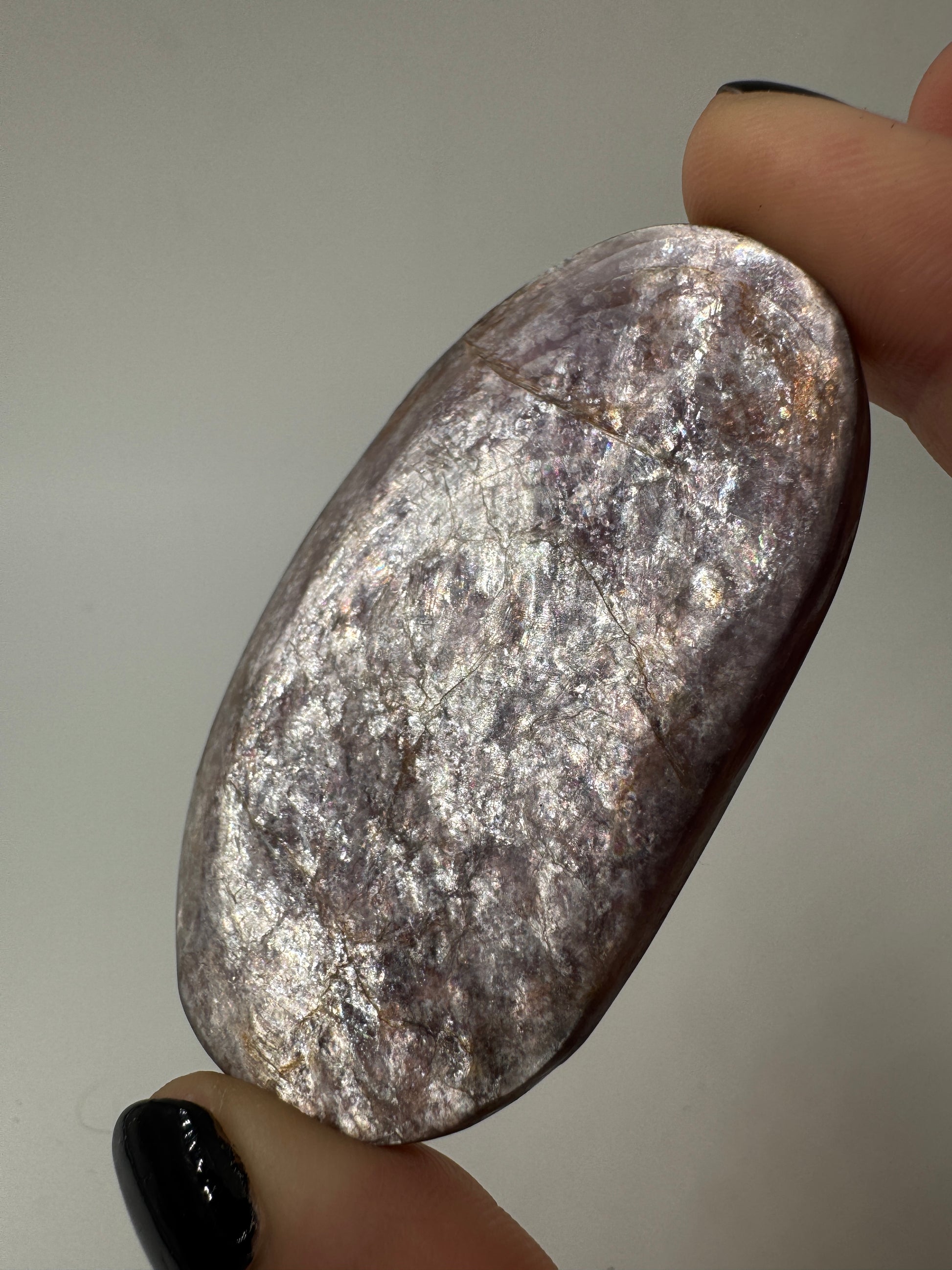 Ein glatt polierter, fliederfarbener Lepidolith-Handstein mit seidig glänzender Oberfläche und dezenten mineralischen Texturen.