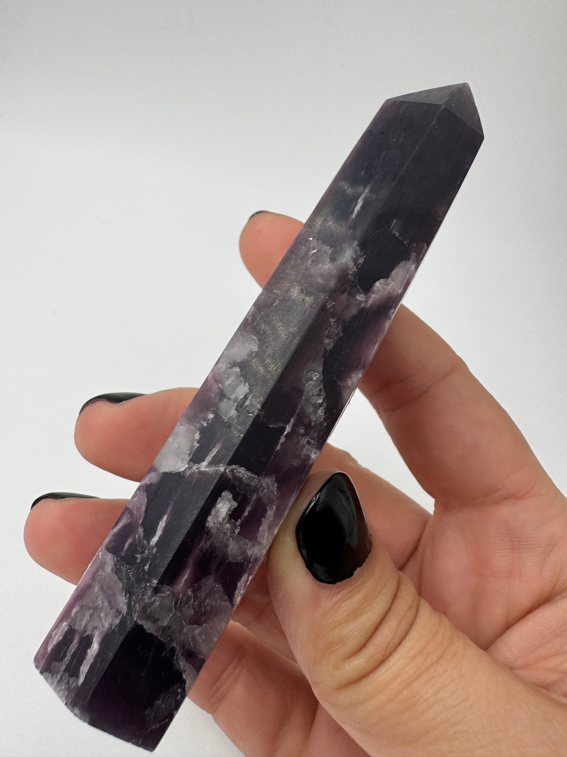 Ein spitz zulaufender, polierter Turm aus fliederfarbenem Lepidolith mit dezent glitzernden Glimmer-Einschlüssen