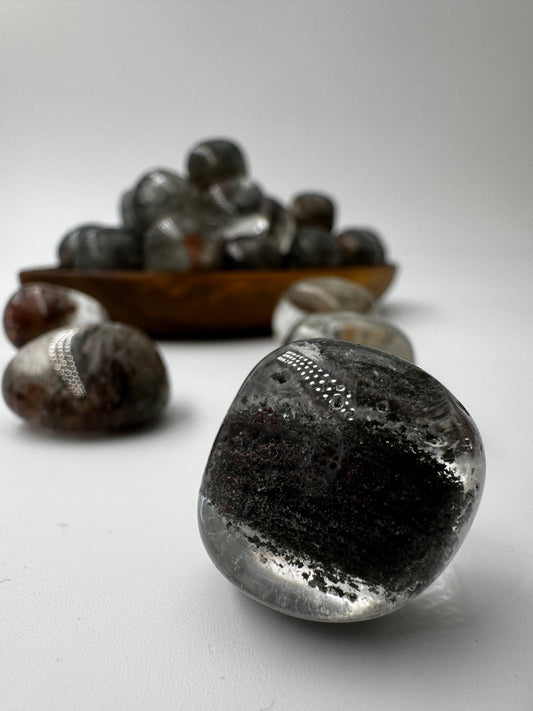 Lodolith Trommelstein mit sichtbaren Mineraleinschlüssen in Grün und Braun, landschaftsartige Inklusionstextur.