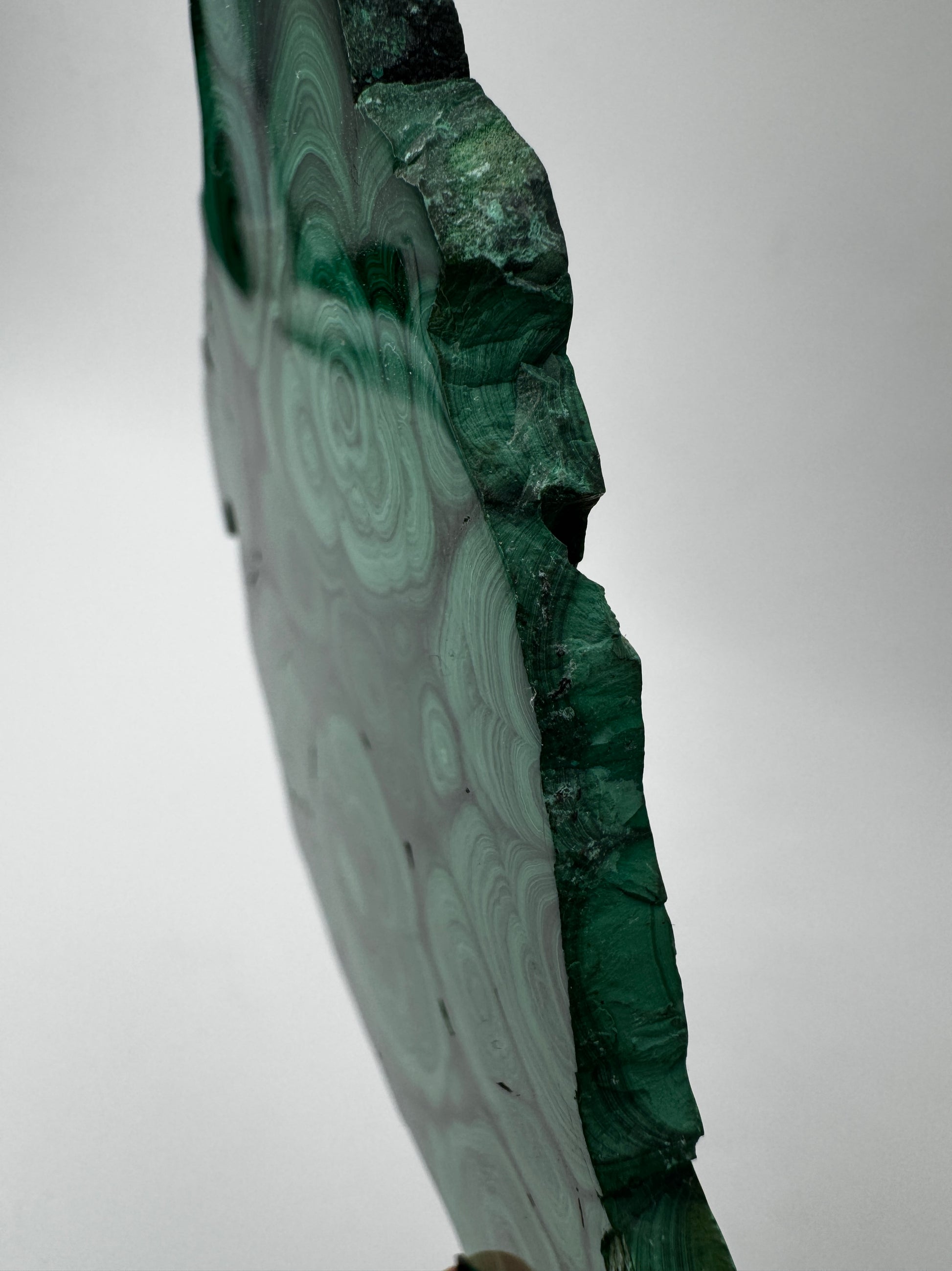 Beidseitig polierter Malachit-Anschliff mit konzentrischen grünen Bändern, 12 × 8 × 0,6 cm, natürliche Seiten.