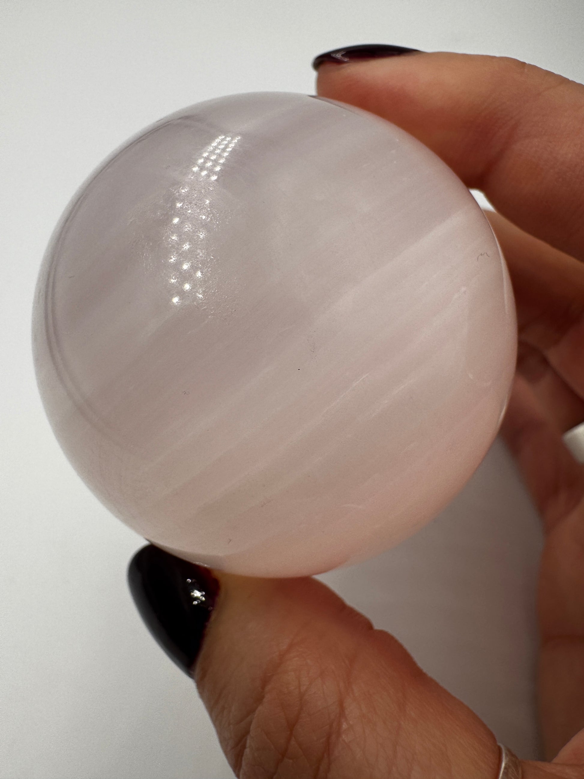 Handpolierte Mangano Calcit Kugel MK39 in zartrosa mit perlmuttartigem Glanz und UV-Fluoreszenz, Durchmesser 5,4 cm.