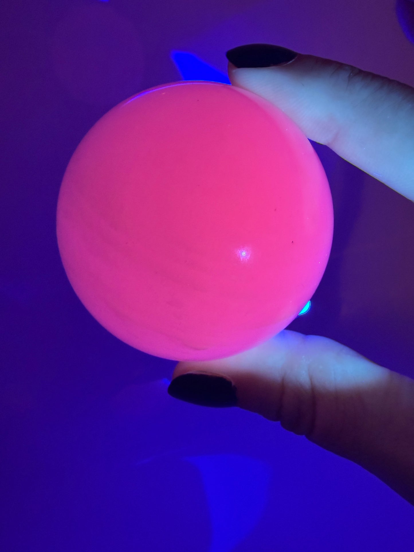 Handpolierte Mangano Calcit Kugel MK39 in zartrosa mit perlmuttartigem Glanz und UV-Fluoreszenz, Durchmesser 5,4 cm.