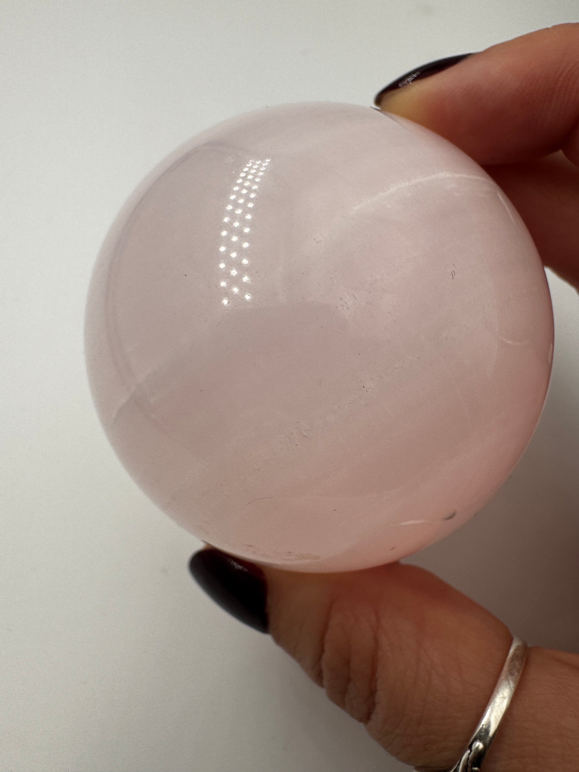 Handpolierte Mangano Calcit Kugel MK53 in zartrosa mit perlmuttartigem Glanz und UV-Fluoreszenz, Durchmesser 5,9 cm.