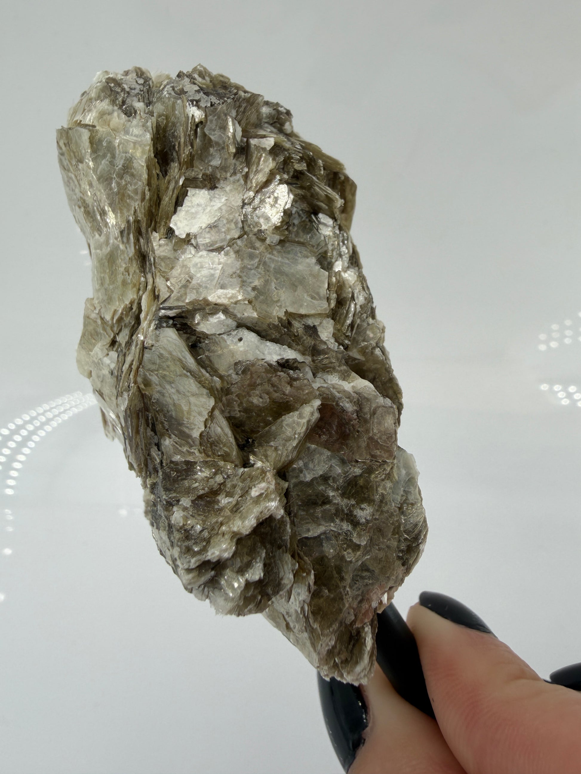 Silbrig glänzender Muskovit-Glimmer auf einem schwarzen Metallständer zur dekorativen Präsentation.