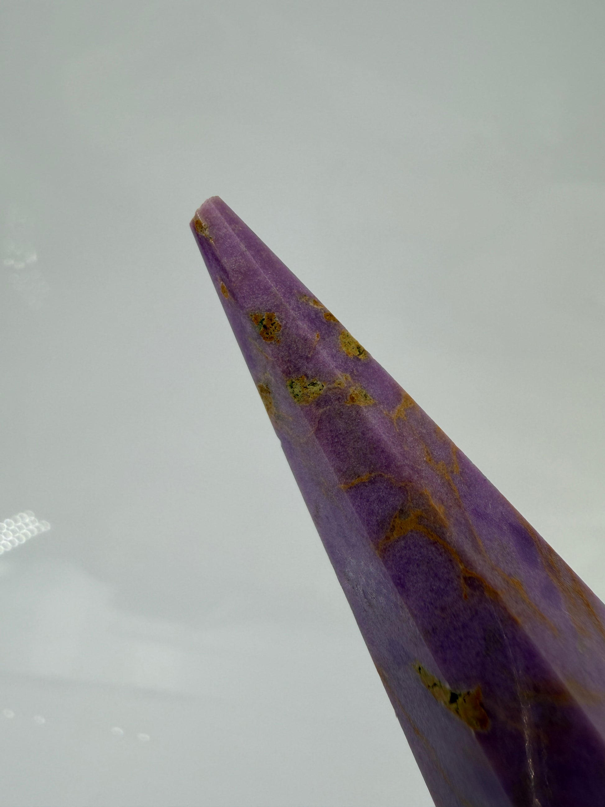 Eine fliederfarbene Phosphosiderit-Stele mit deutlich sichtbarer, natürlicher Bruchstelle an der Spitze und gelben Mineraladern.