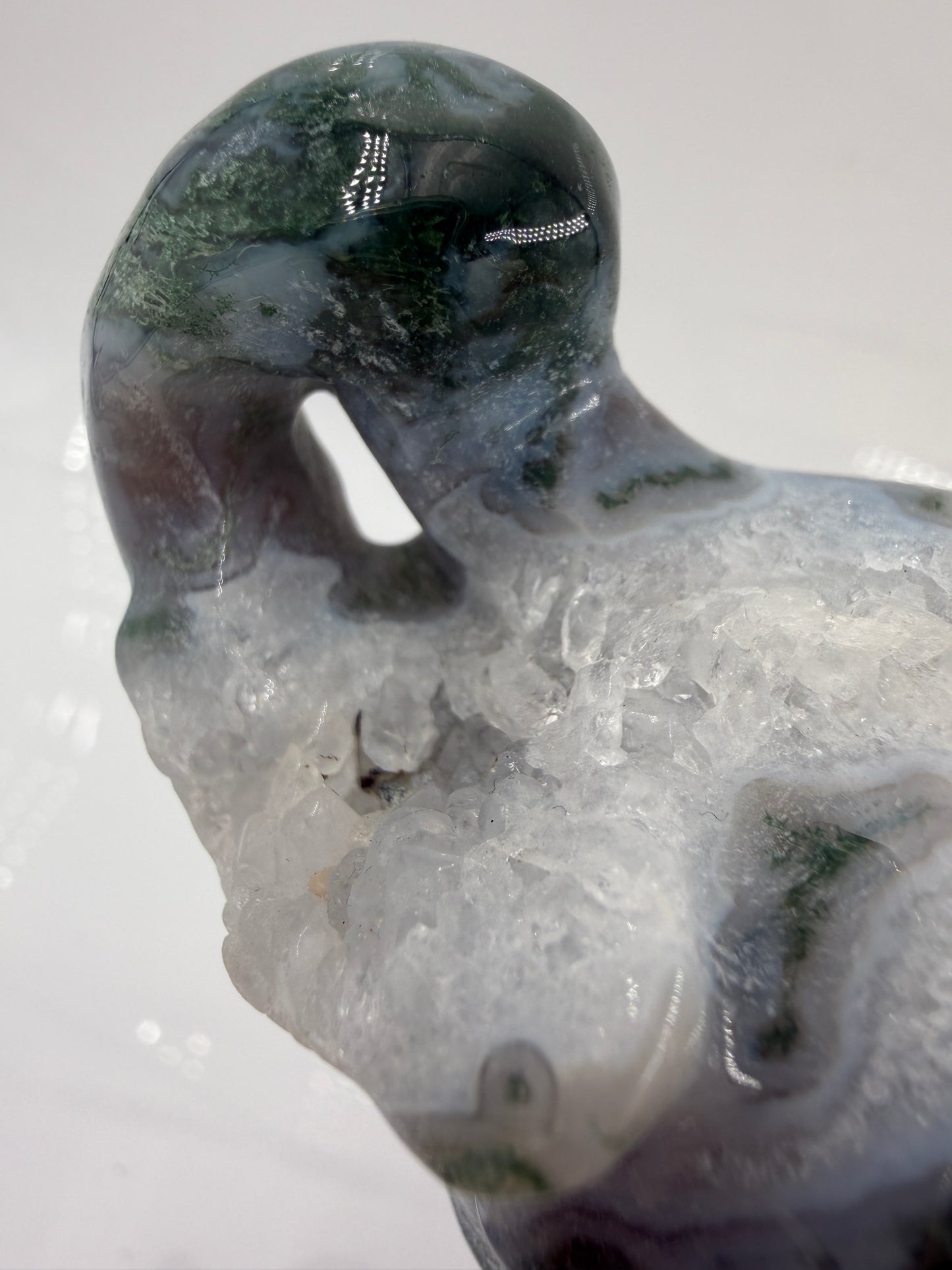 Eine polierte Skulptur in Form eines Flaschenkürbisses aus Moosachat mit tiefgrünen, moosartigen Strukturen in einer milchig-transparenten Matrix.