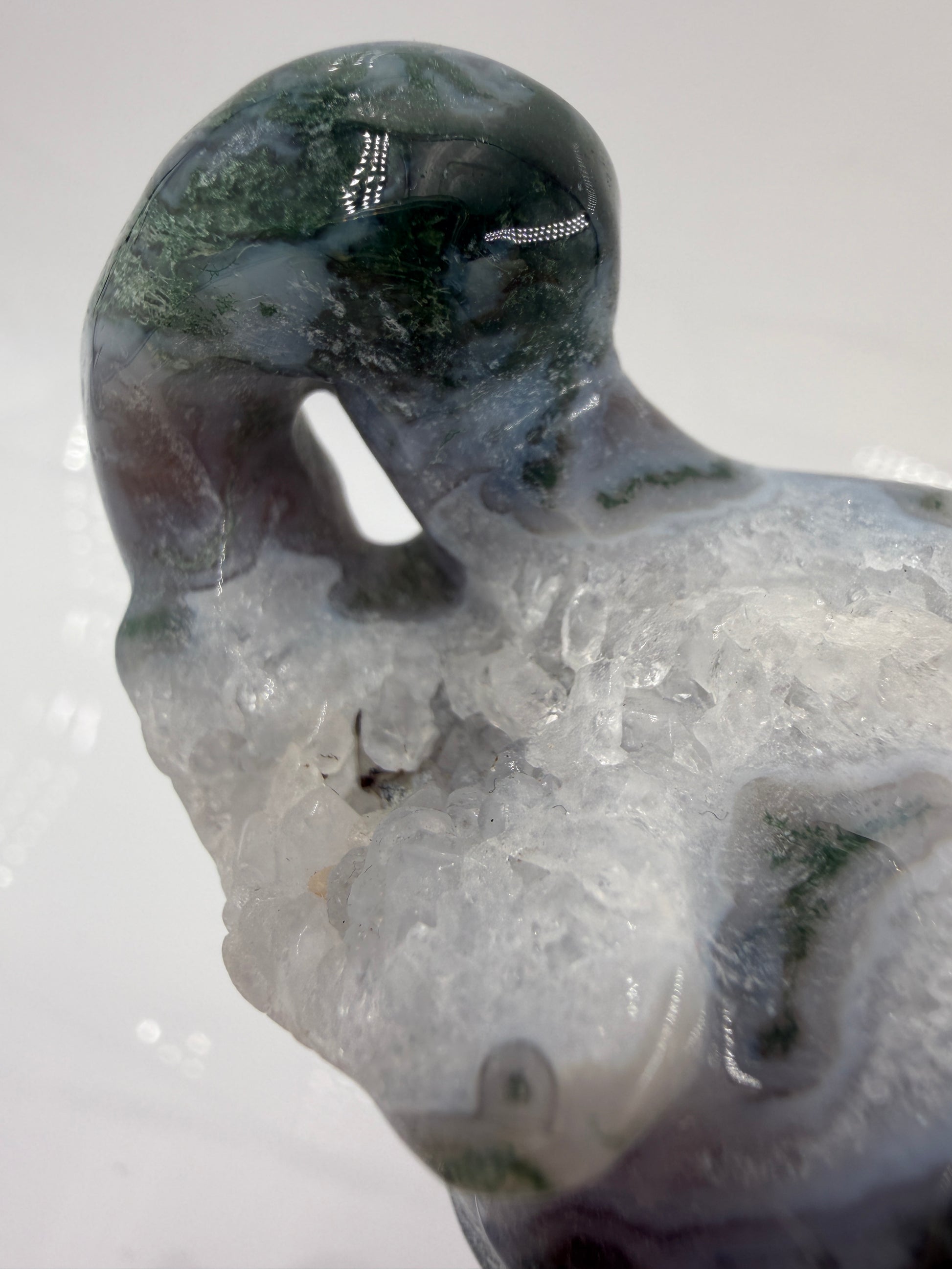 Eine polierte Skulptur in Form eines Flaschenkürbisses aus Moosachat mit tiefgrünen, moosartigen Strukturen in einer milchig-transparenten Matrix.