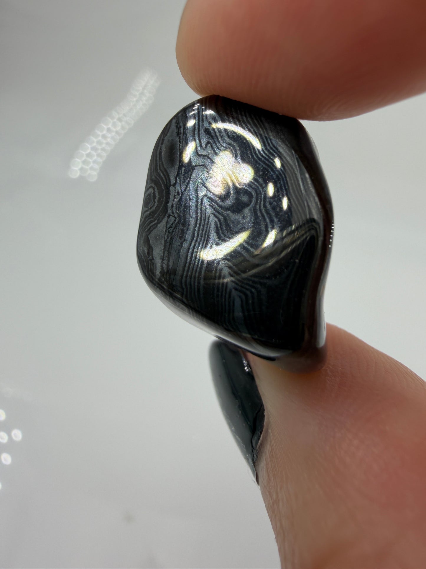 Tiefschwarze, metallisch glänzender Psilomelan-Trommelstein mit silbrig schimmernden, fließenden Linienstrukturen.
