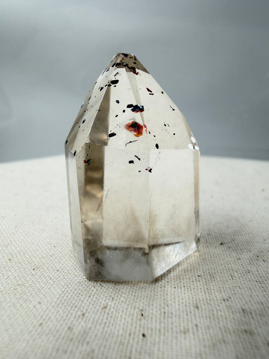 Quarz Spitze mit Hämatit-Plättchen QH12, 3,5 cm Höhe, mit silbrig glänzenden Hämatit-Einschlüssen im transparenten Quarz.