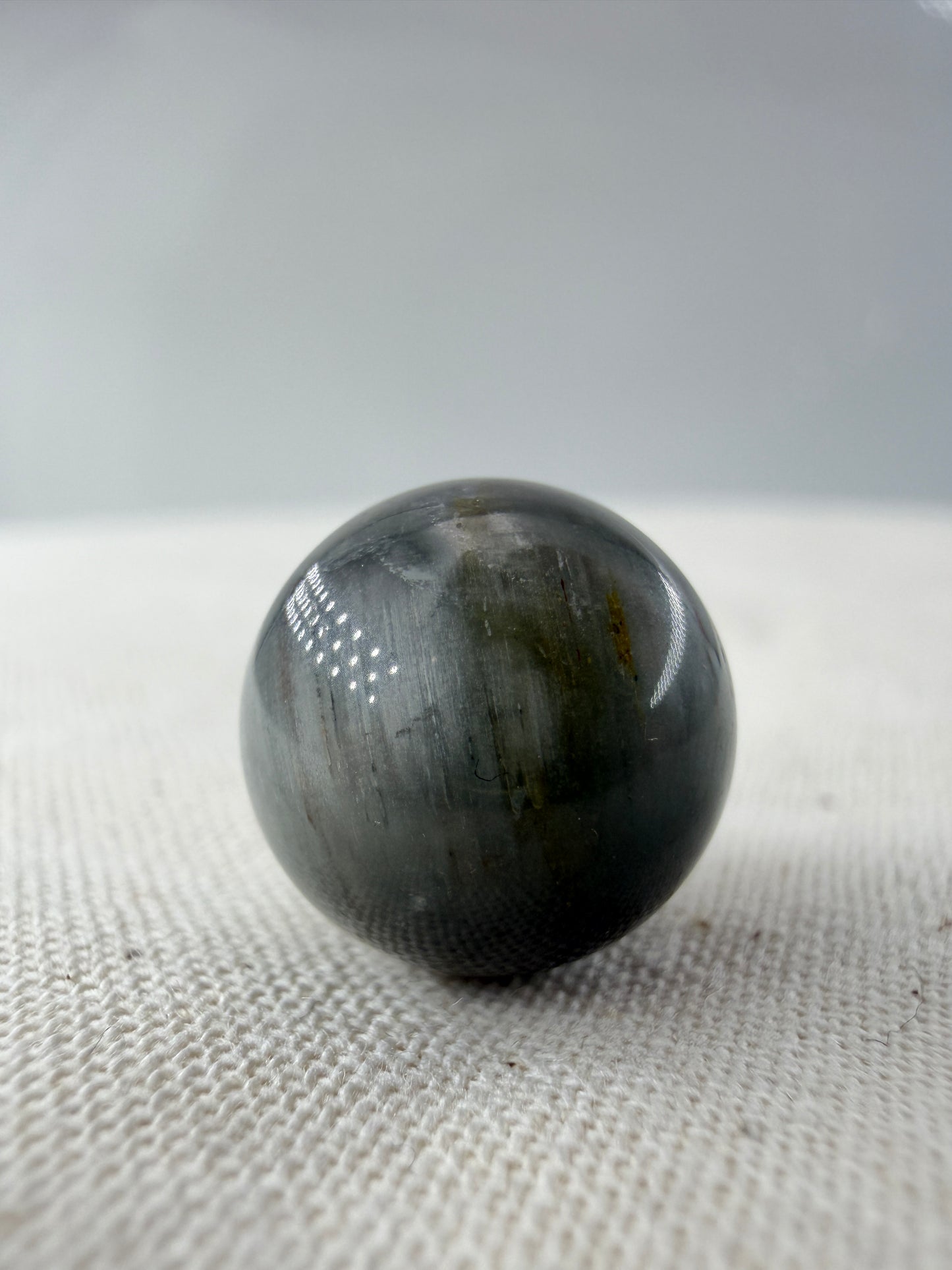 Rabbit Hair Minikugel aus Quarz mit grauen nadelförmigen Mineraleinschlüssen, Ø 1,1–1,3 cm.