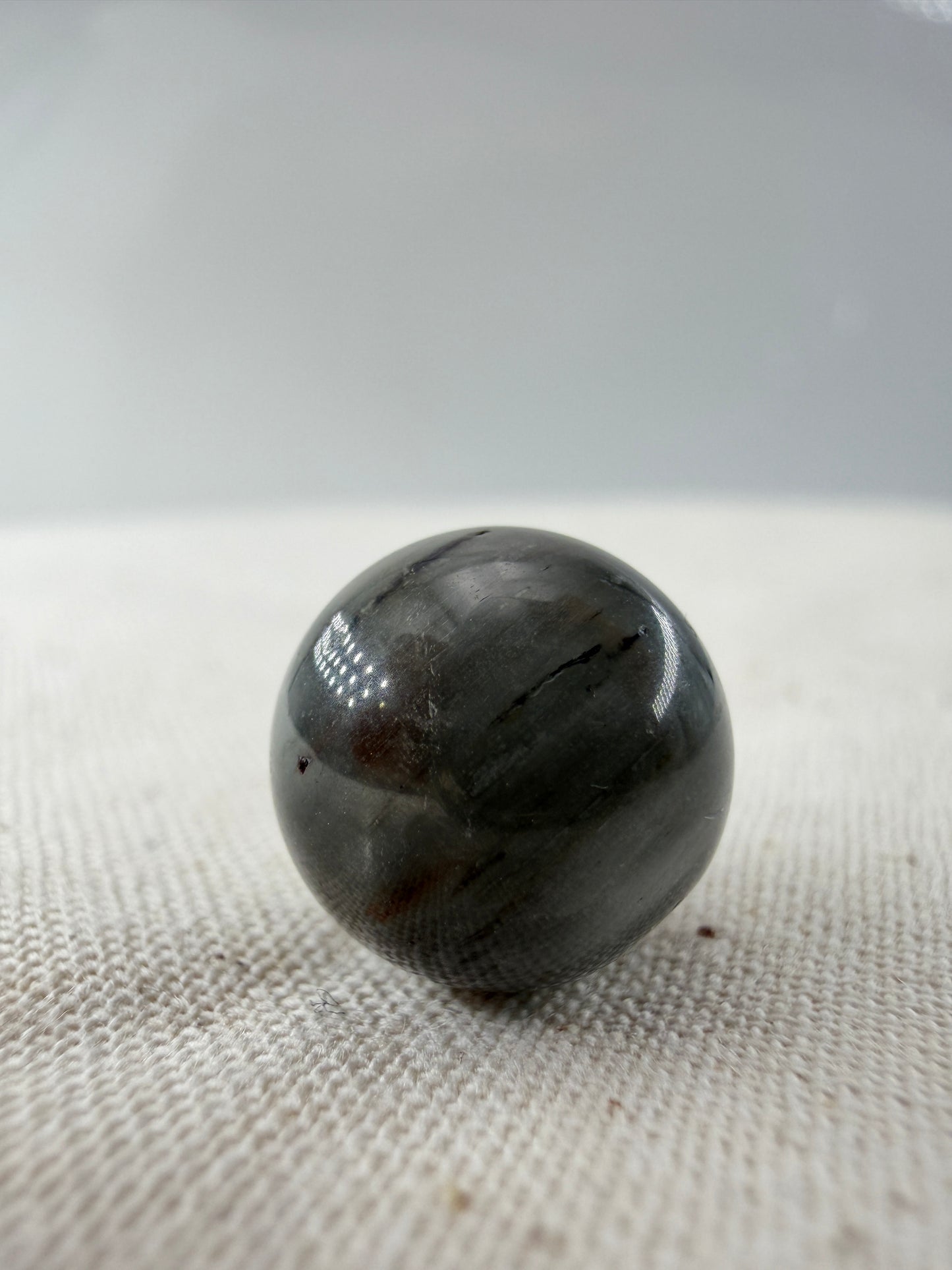 Rabbit Hair Minikugel aus Quarz mit grauen nadelförmigen Mineraleinschlüssen, Ø 1,1–1,3 cm.