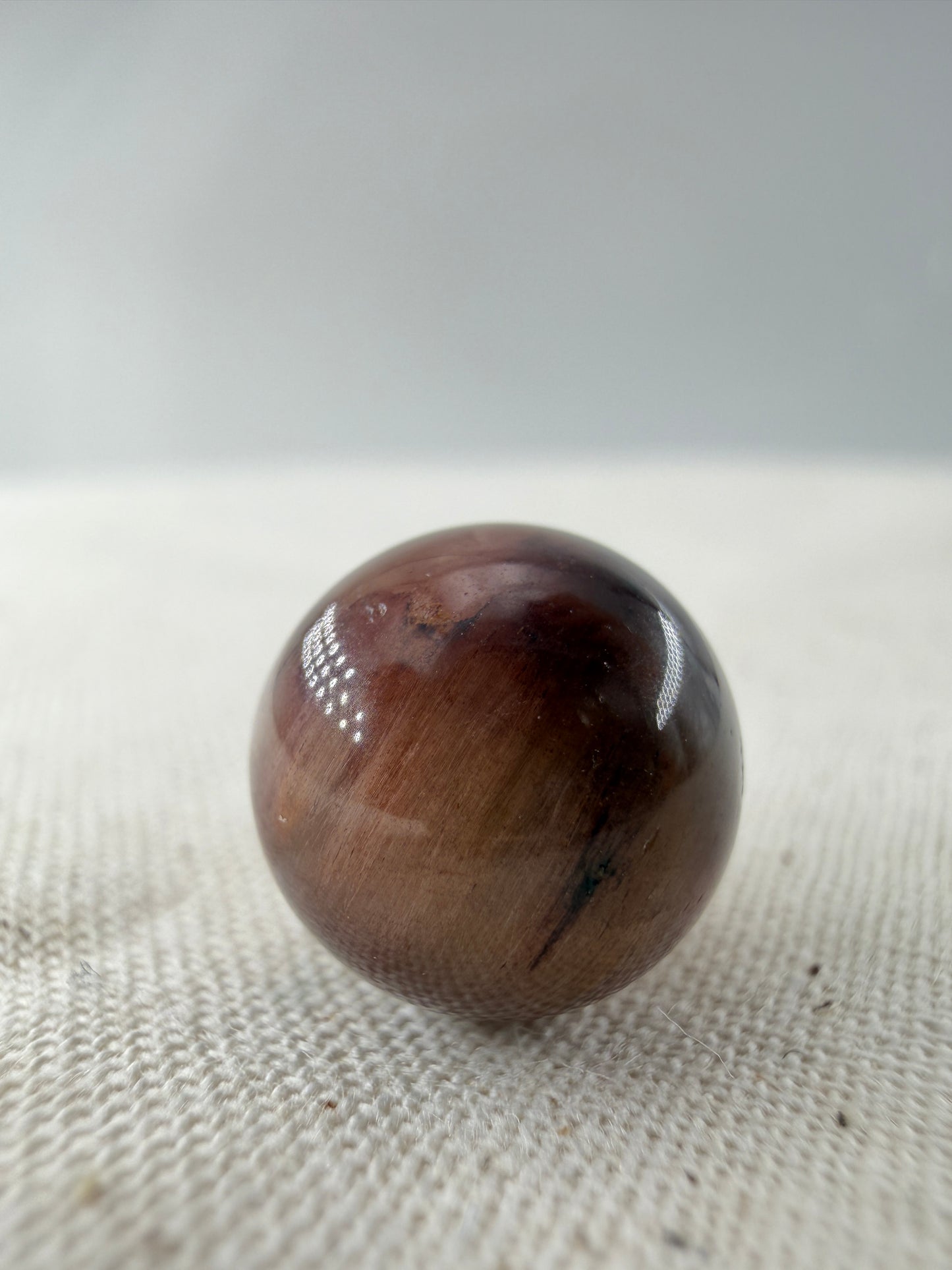Rabbit Hair Minikugel aus Quarz mit roten nadelförmigen Mineraleinschlüssen, Ø 1,1–1,3 cm.