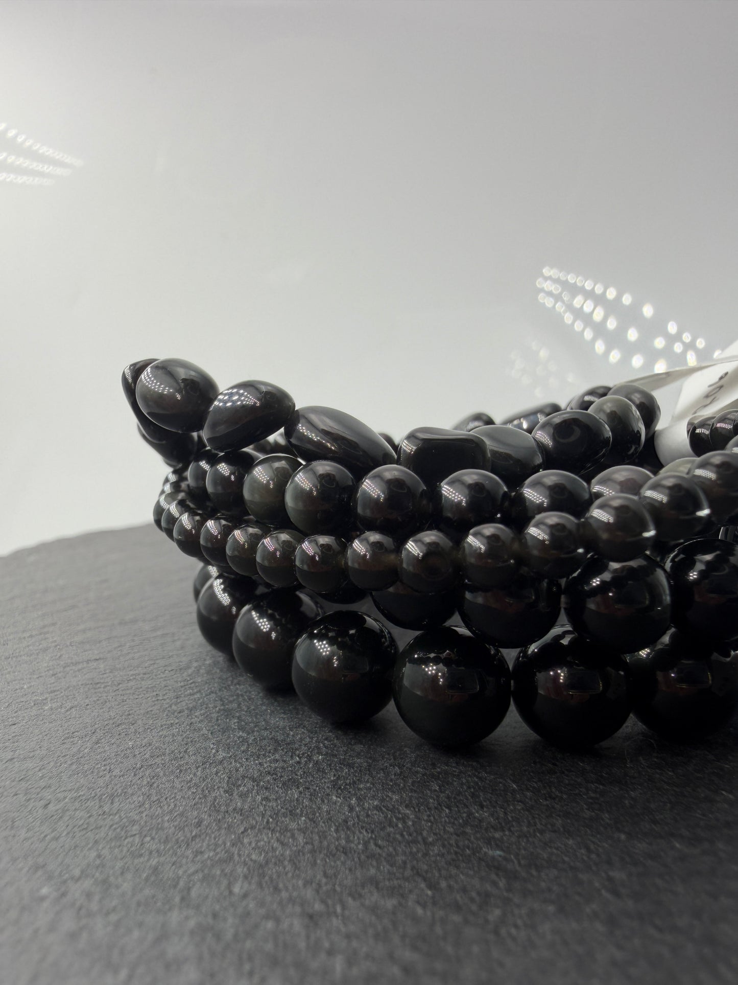 Kugelarmband aus Regenbogen-Obsidian mit irisierenden Farbringen in Violett und Grün.
